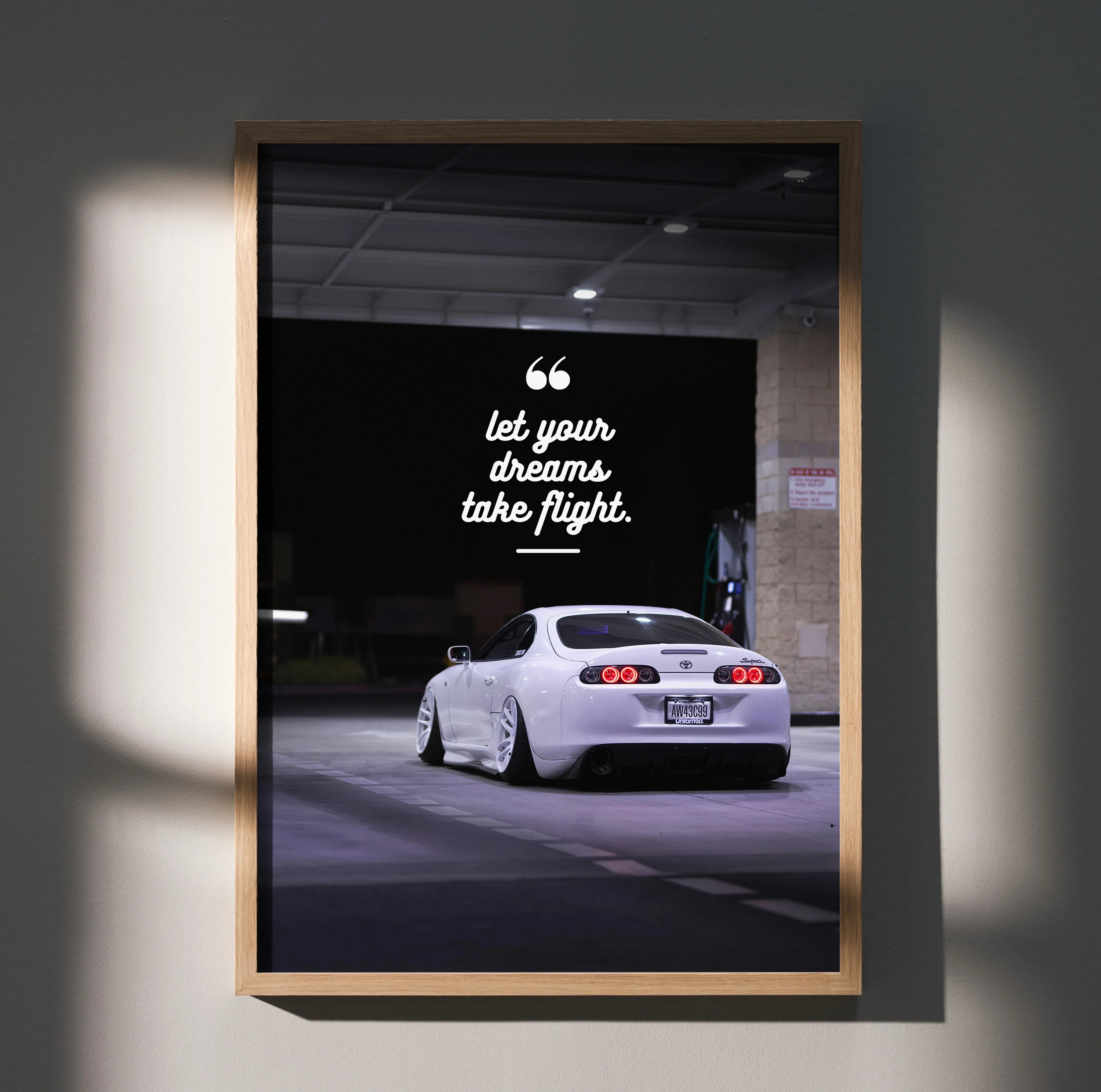 Motivational wall art poster featuring a white Toyota Supra Mk4 with inspiring text "Let your dreams take flight" against a.