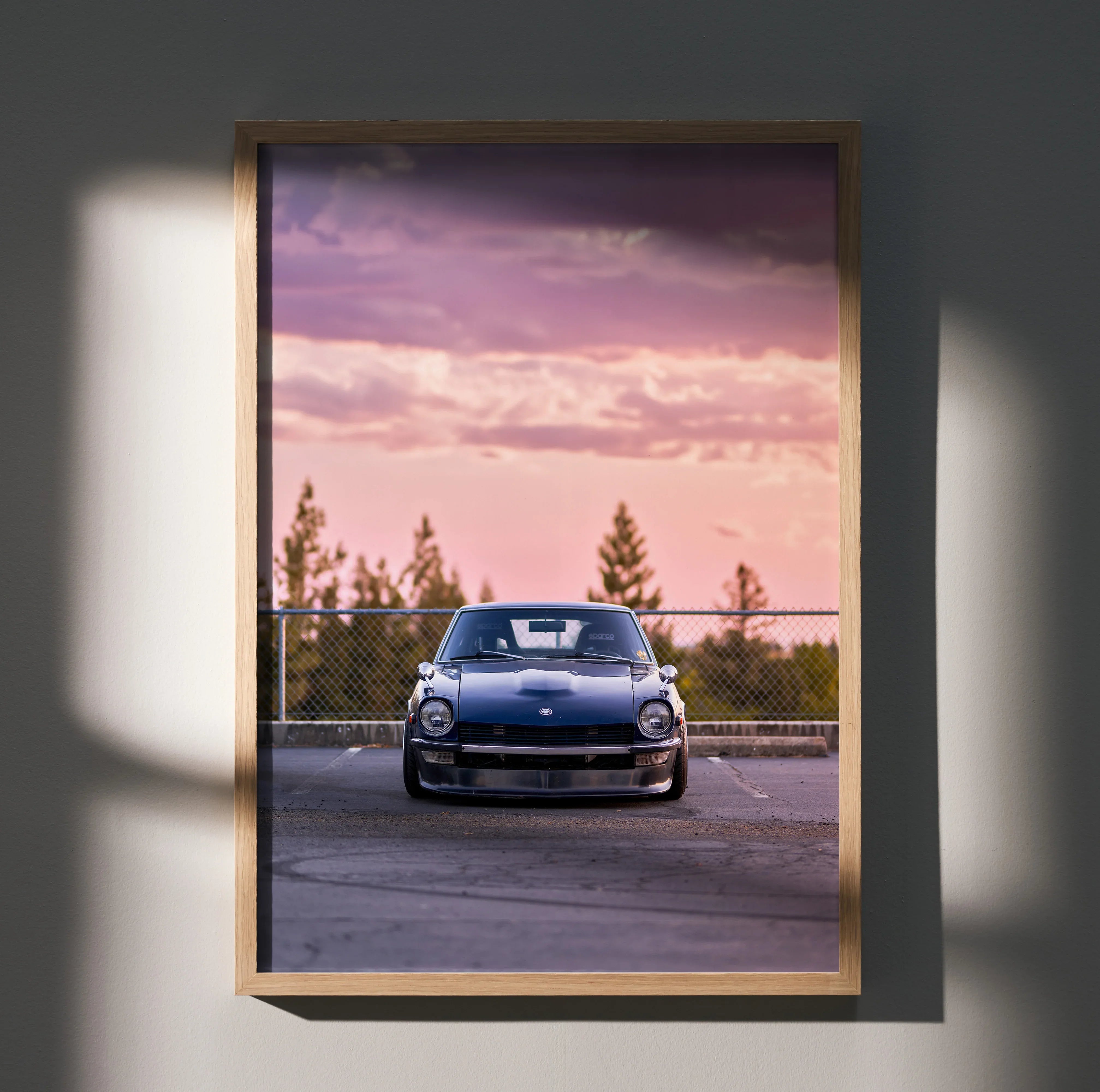 Nissan 240z poster wall art with car at sunset and pine trees background in wooden frame.
