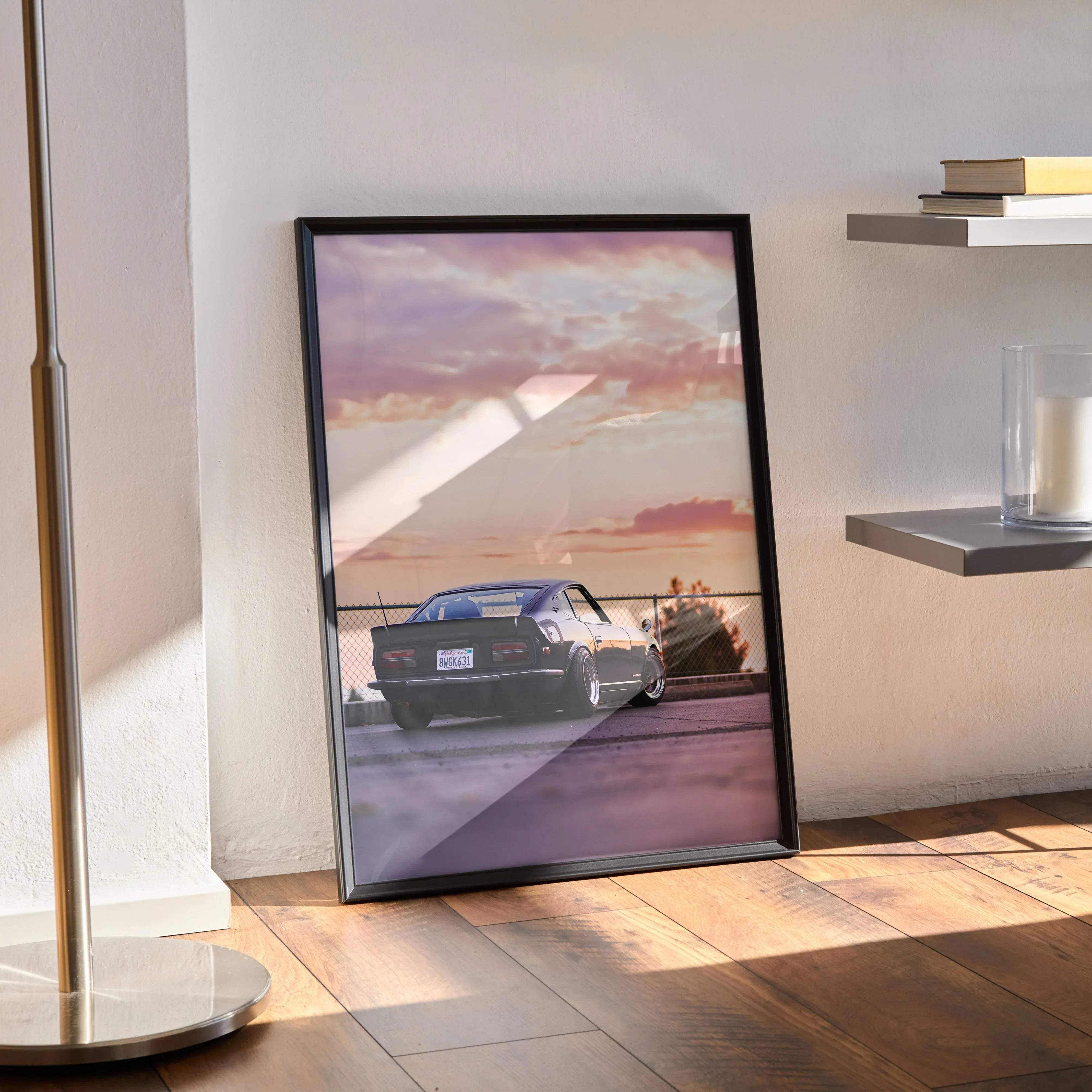 Black-framed poster featuring a sleek dark-colored nissan 240z sports car on asphalt under a pink and purple sunset sky