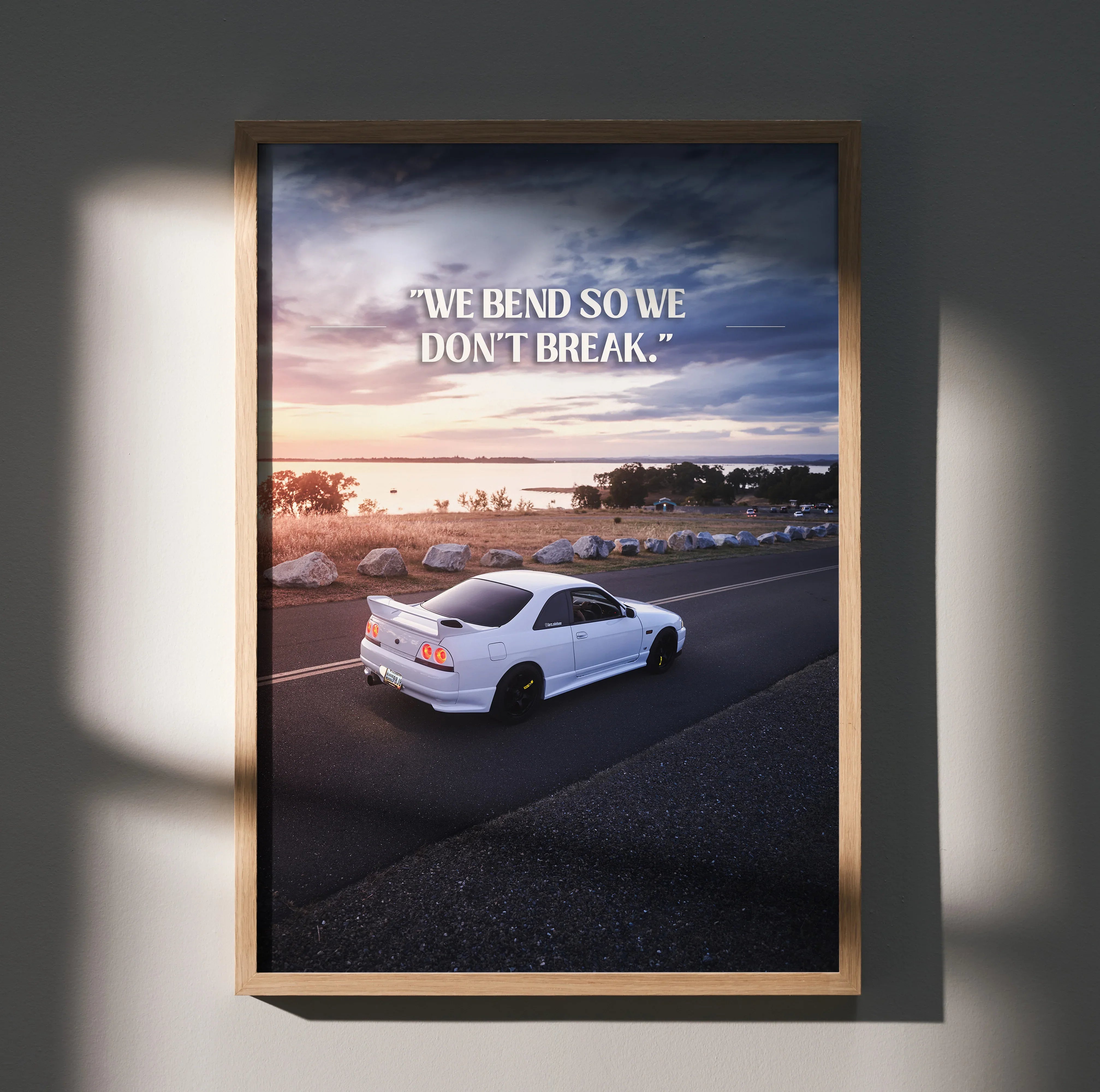 Motivational poster wall art featuring a white Nissan R33 Skyline GTS-T on coastal road at sunset with inspiring text.