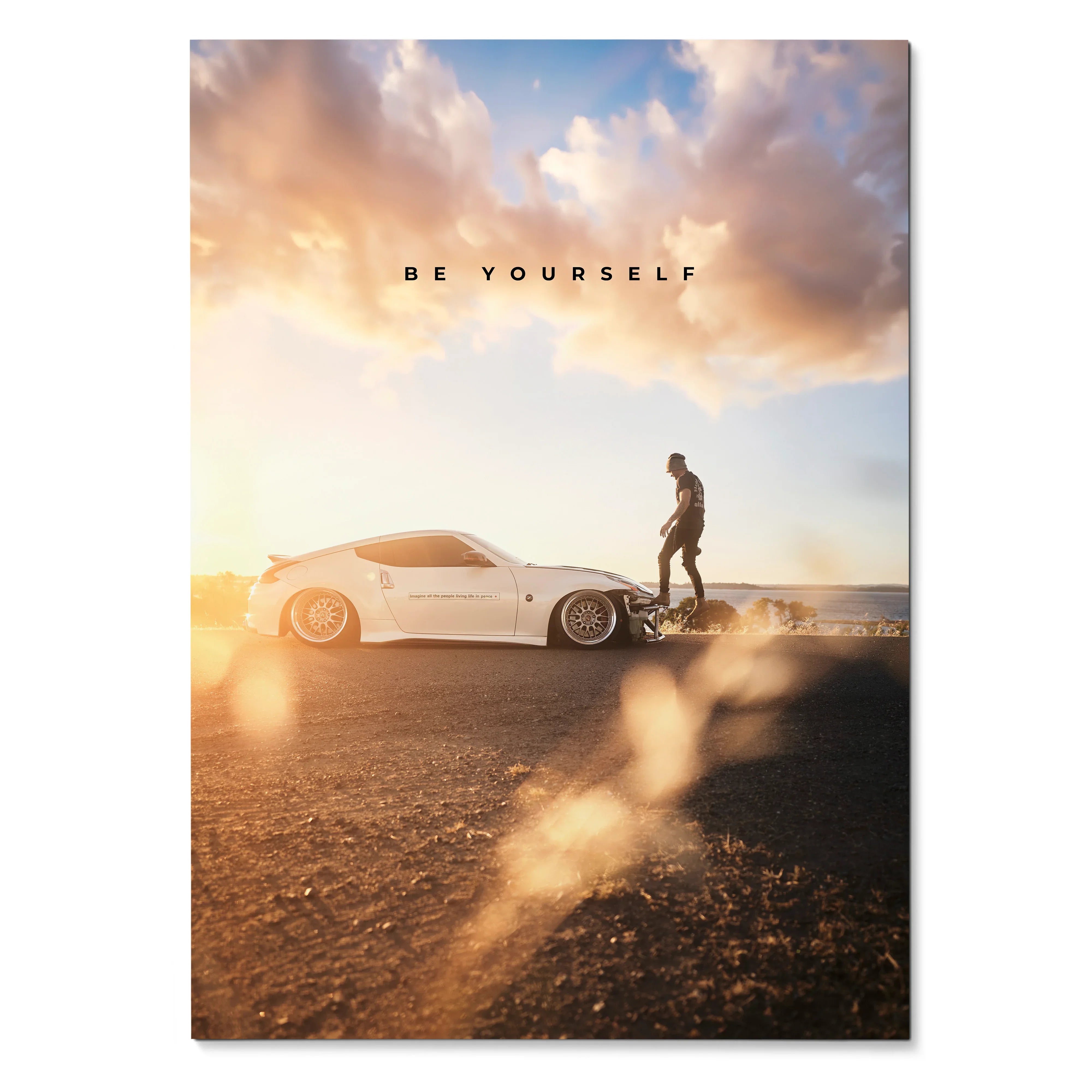 Motivational poster wall art with white Nissan 370z and person standing at sunset under colorful sky.