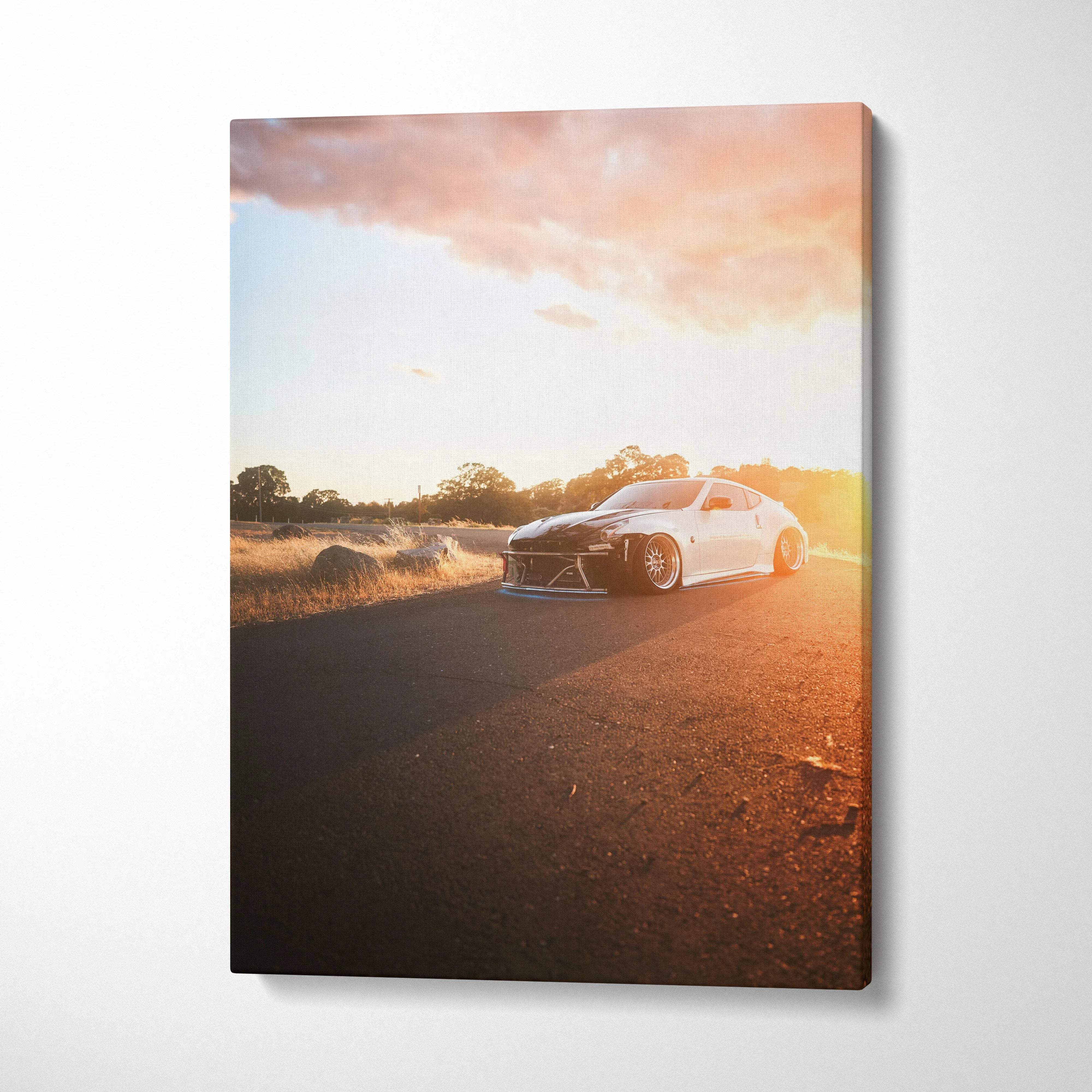 Nissan 370z driving on road at sunset canvas wall art with warm sky and golden light.