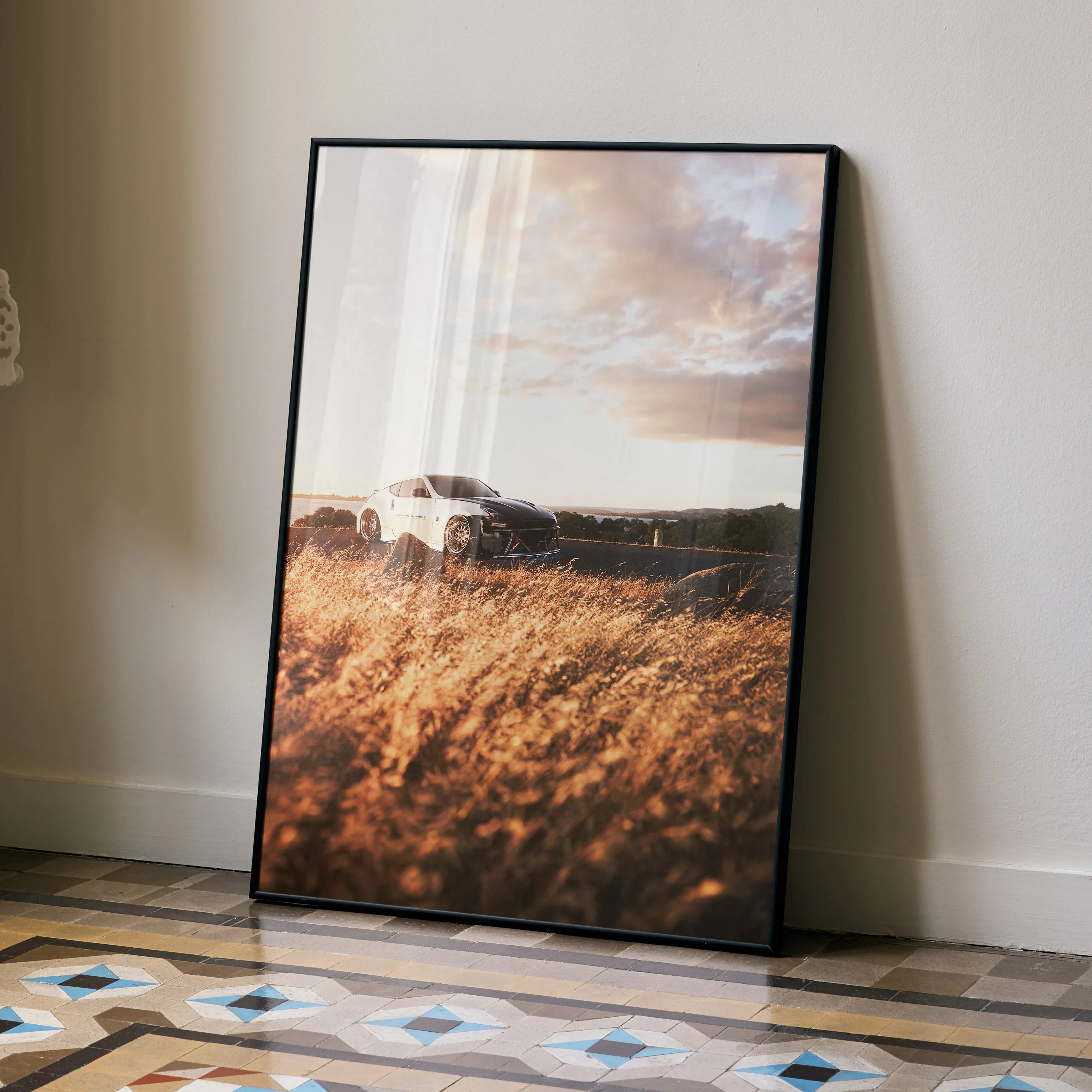 Nissan 370z poster featuring a high-resolution sunset scene with tall grass, framed wall art leaning against a beige wall.