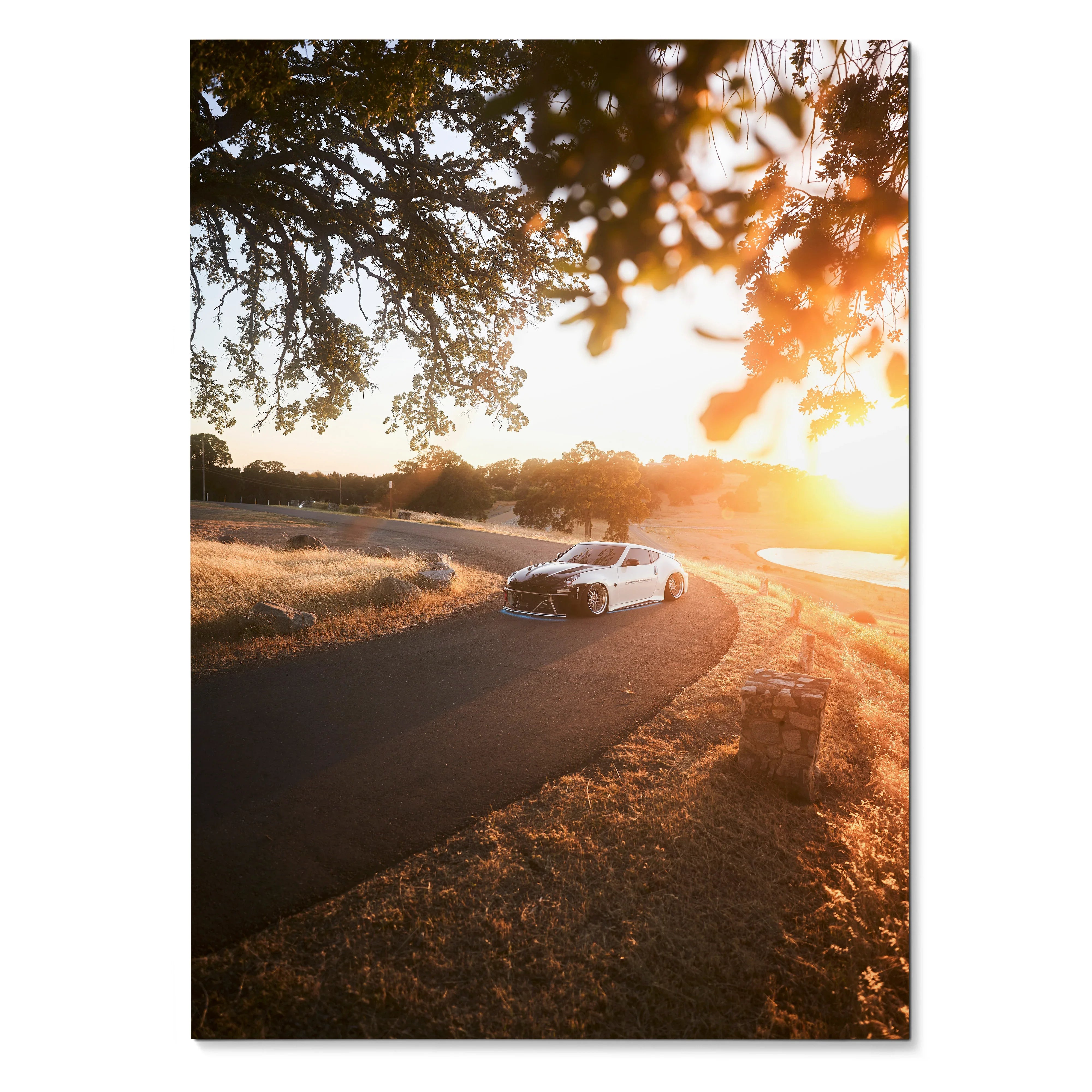 Nissan 370z cruising on winding road at sunset poster wall art with warm golden tones.