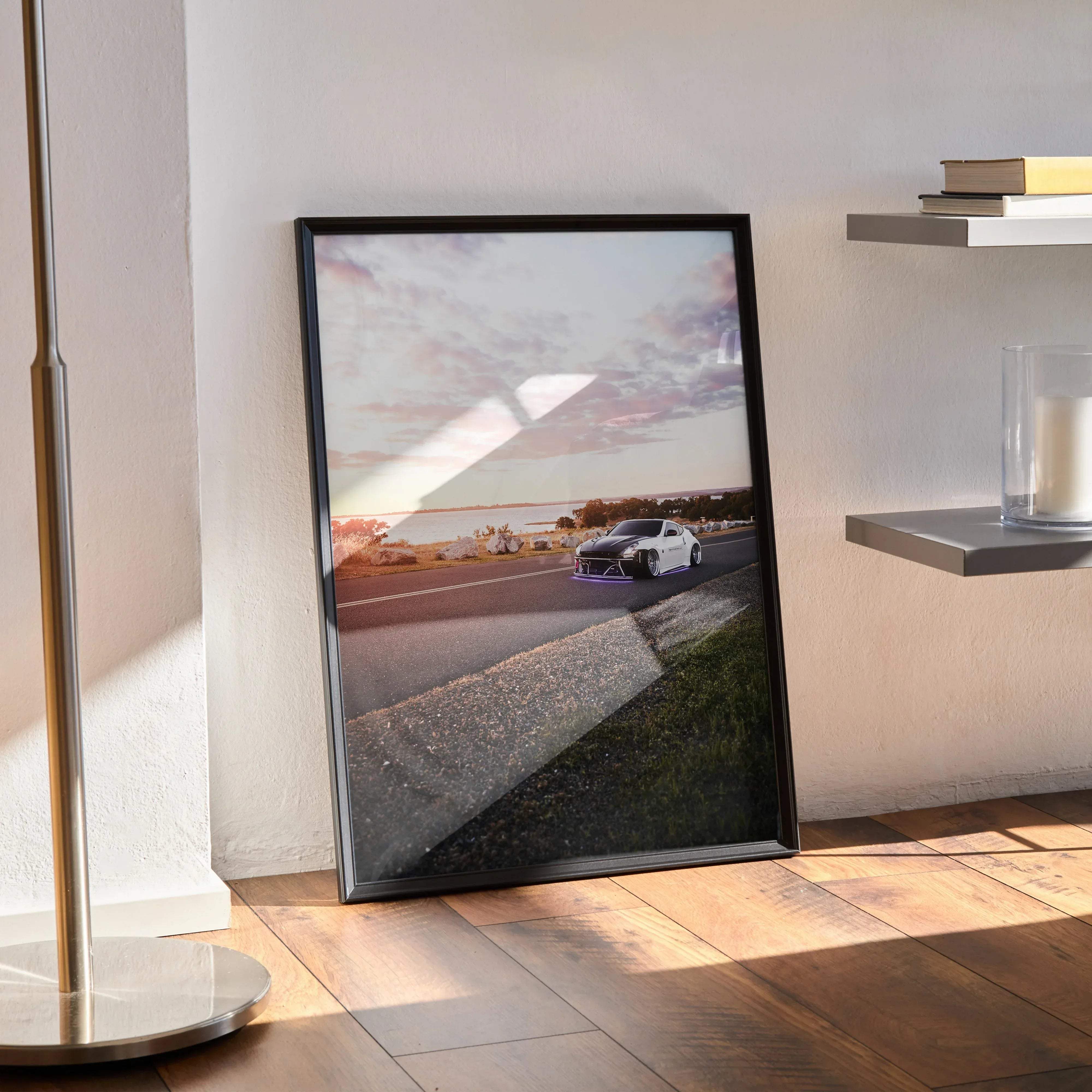 Black-framed wall art of a white Nissan 370z with purple underglow driving on a coastal road at sunset poster
