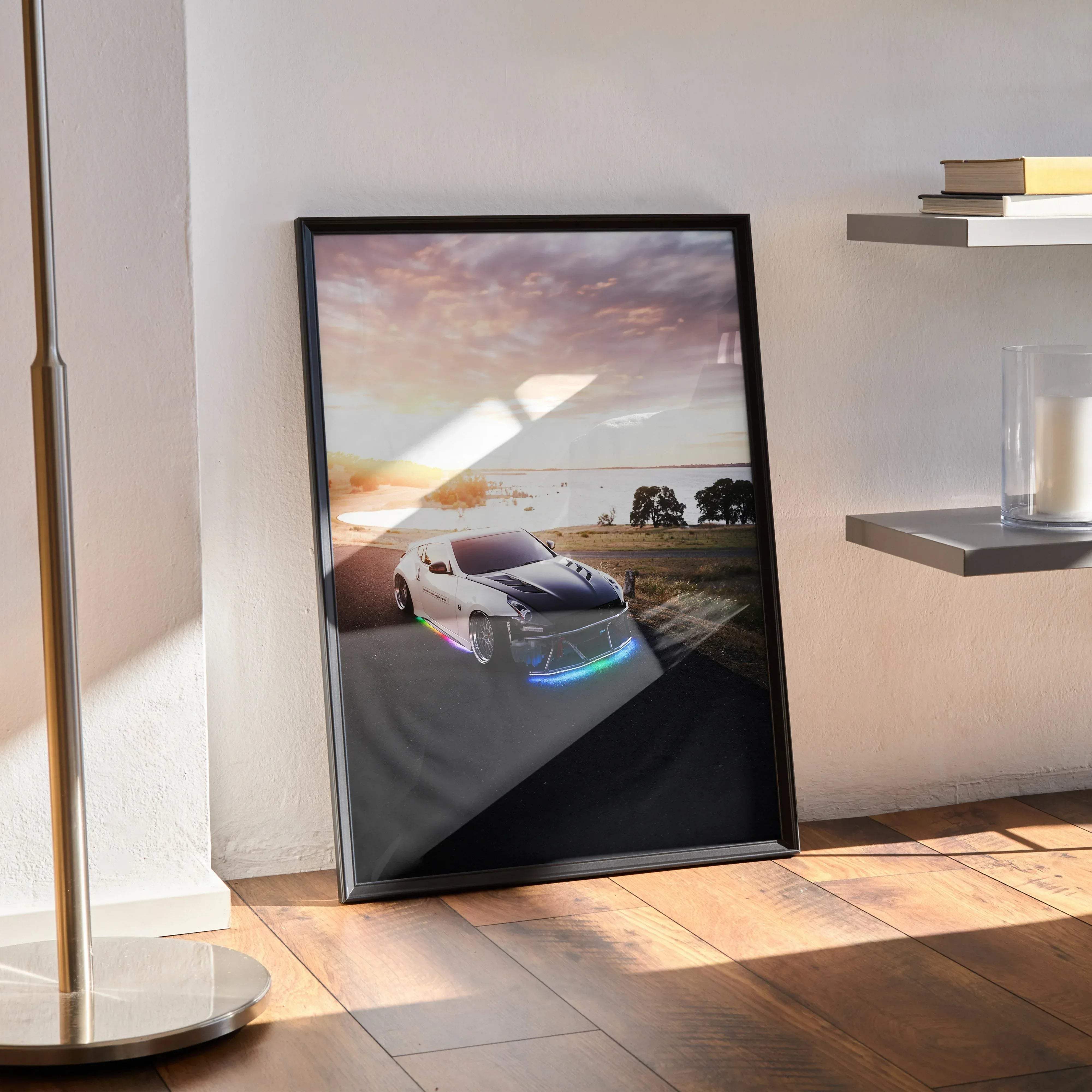 Black-framed poster of a white nissan 370z sports car with blue led lighting set against a sunset landscape