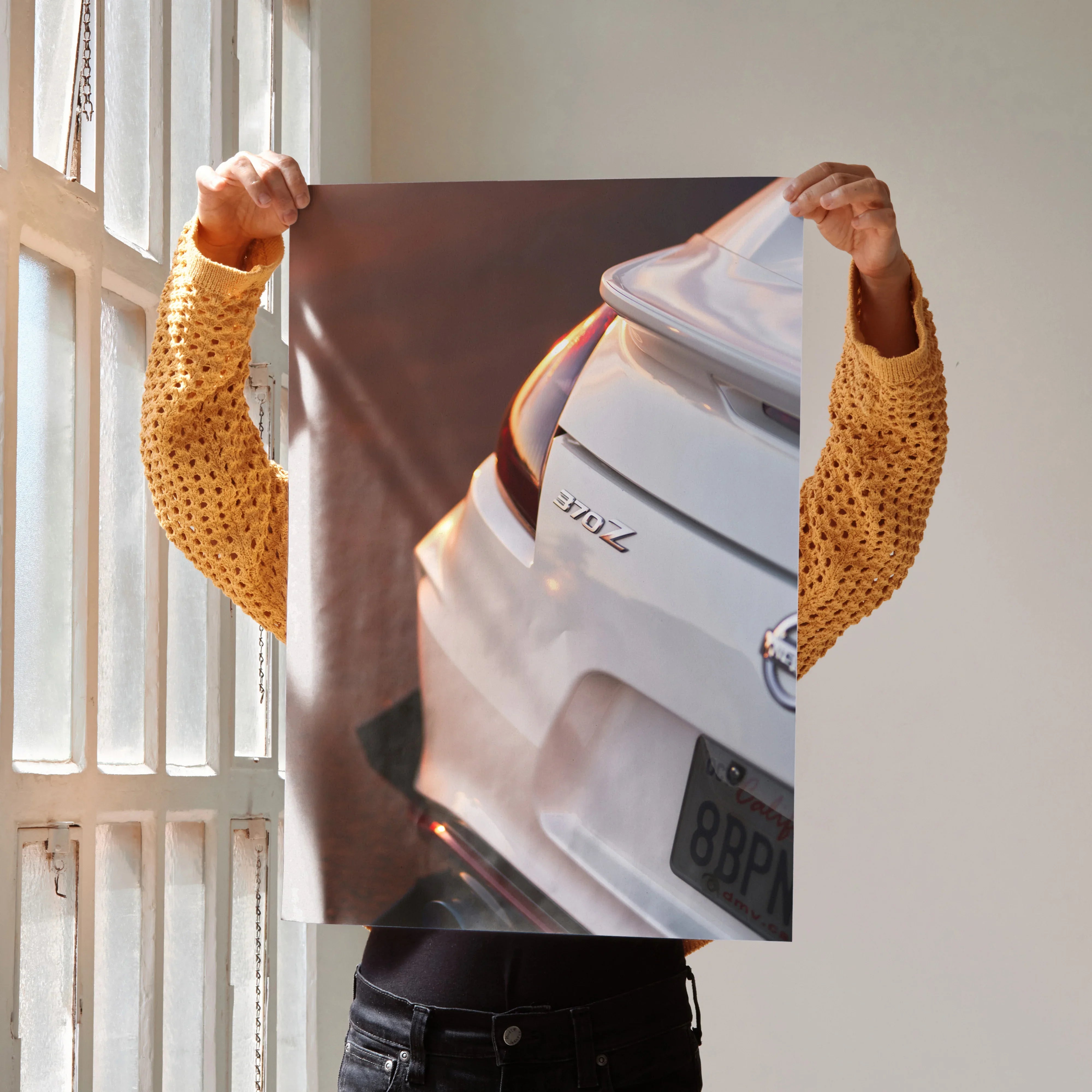 Nissan 370z rear close-up poster held by person in yellow sweater wall art.
