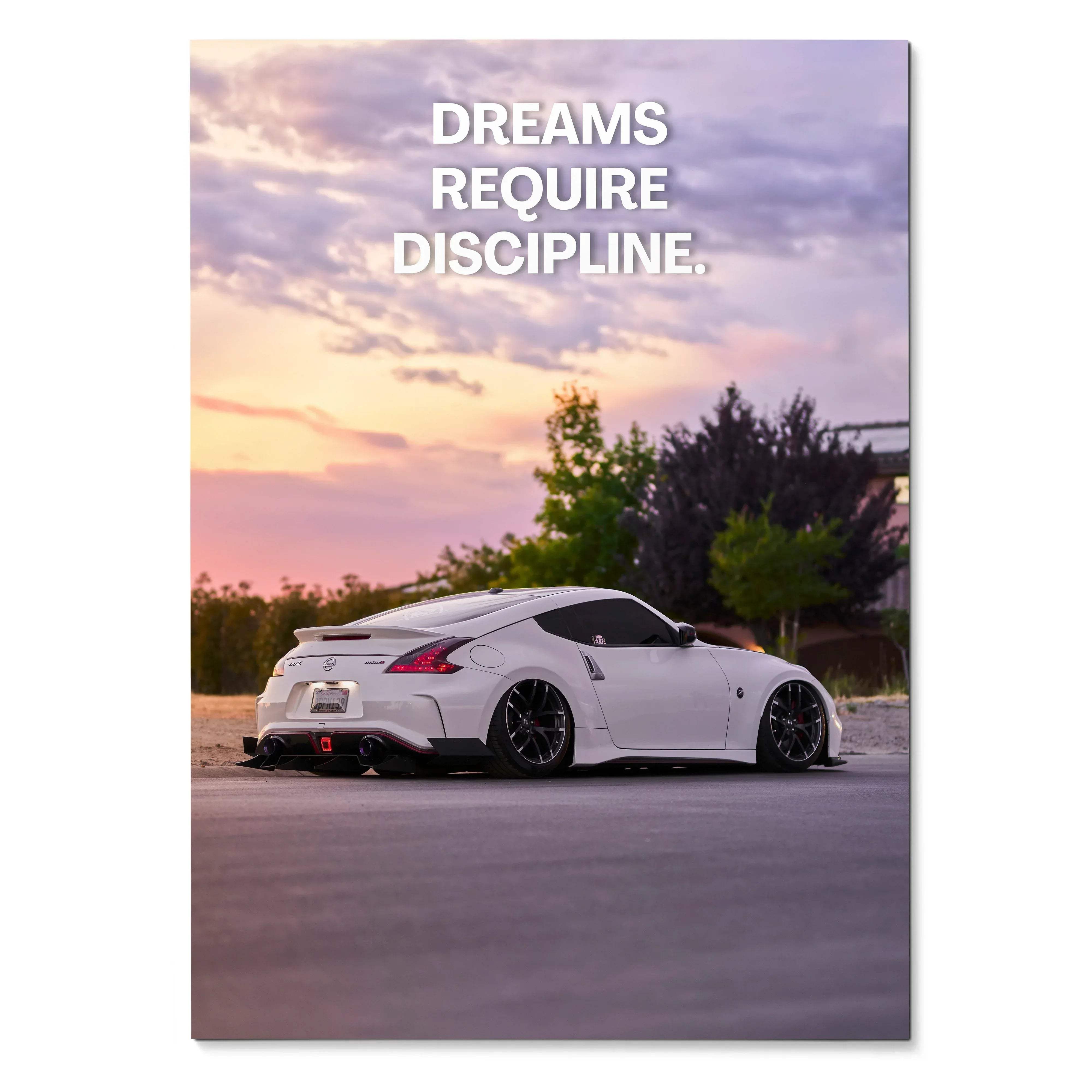 Motivational poster wall art featuring a white Nissan 370z with sunset sky and inspiring text "Dreams Require Discipline".