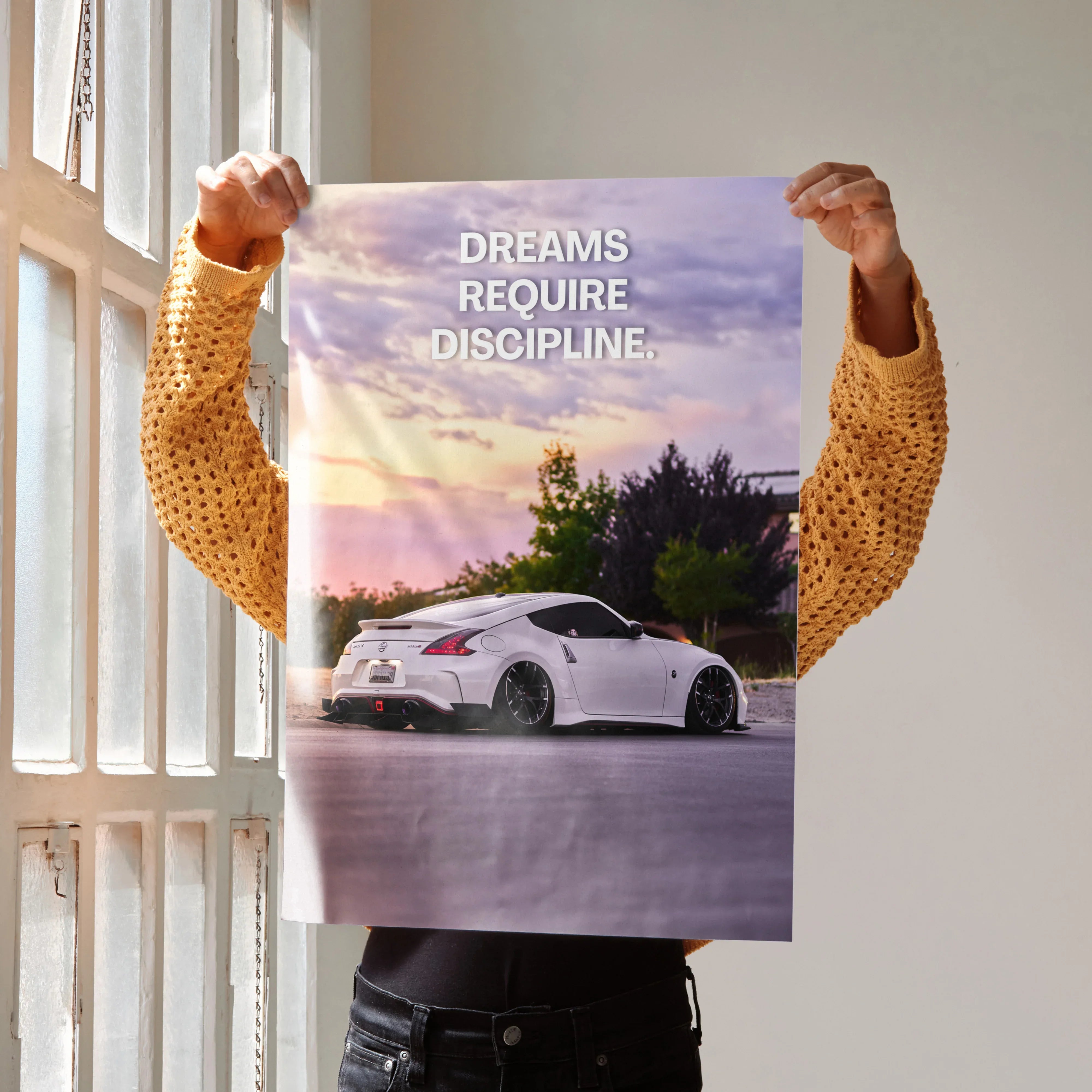 Motivational poster wall art featuring a white Nissan 370z with "Dreams Require Discipline" text against a sunset sky.
