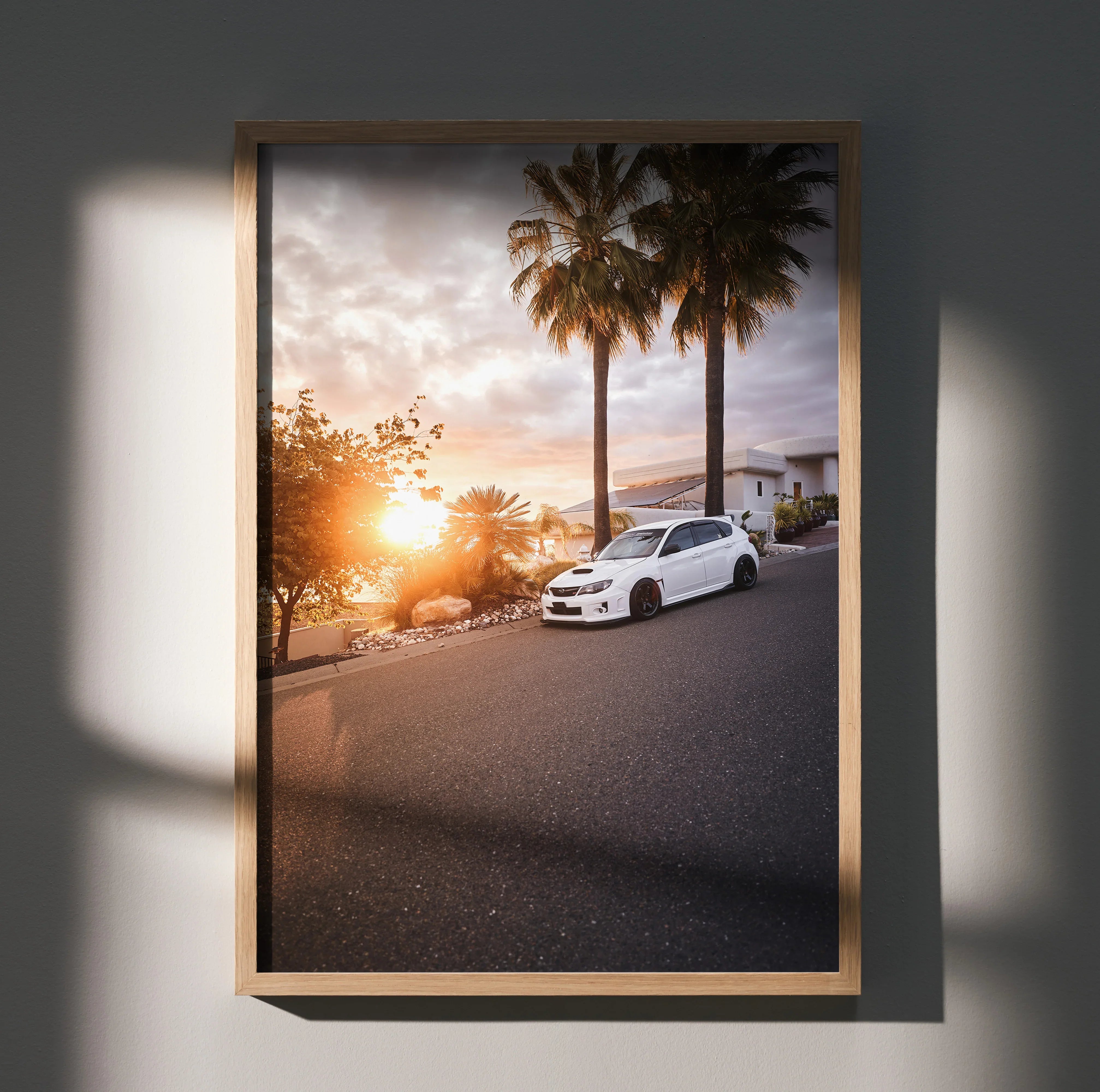 Subaru WRX STI parked by palm trees at sunset automotive poster wall art in wooden frame.