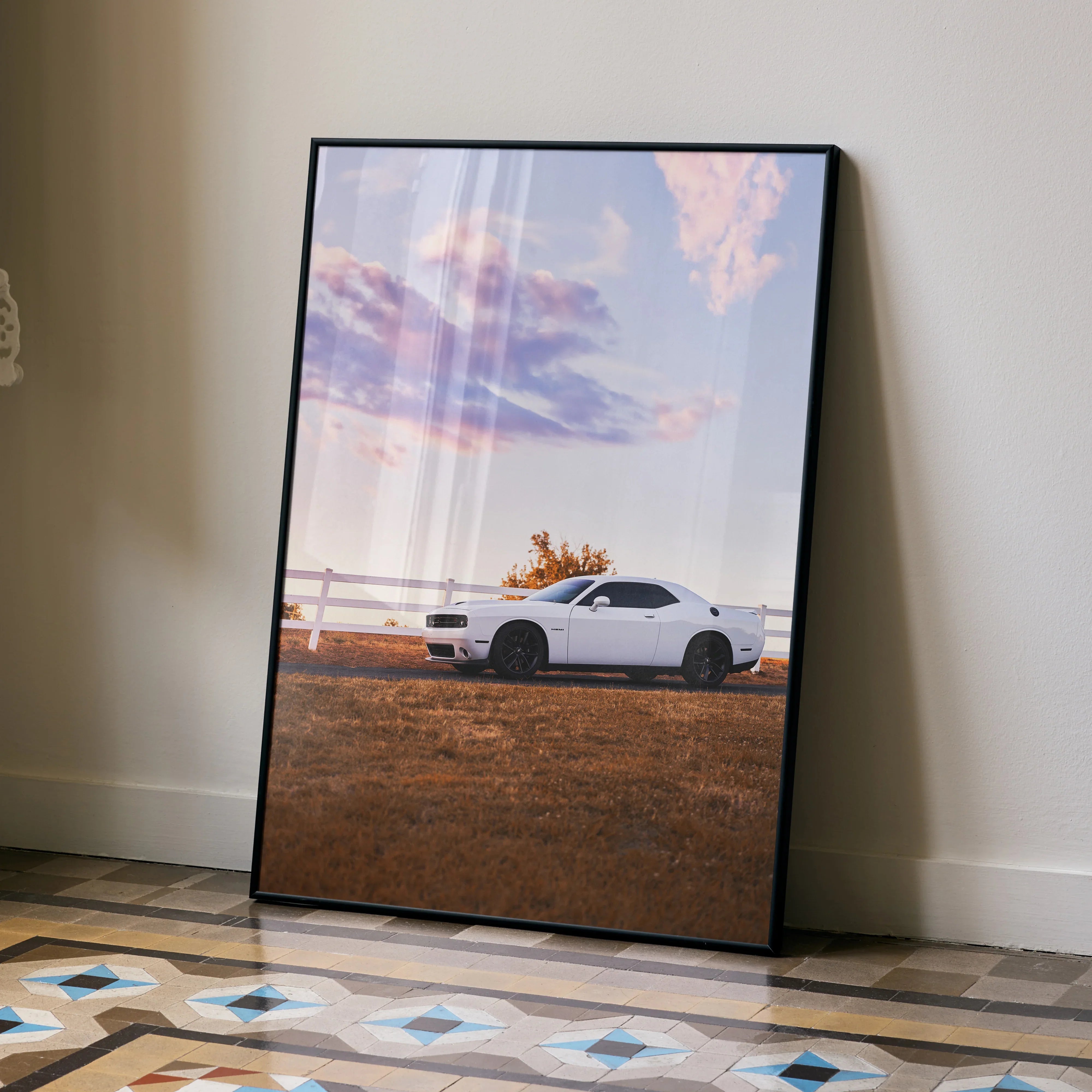 Dodge Challenger parked in a field at sunset, framed wall art poster with vibrant sky.