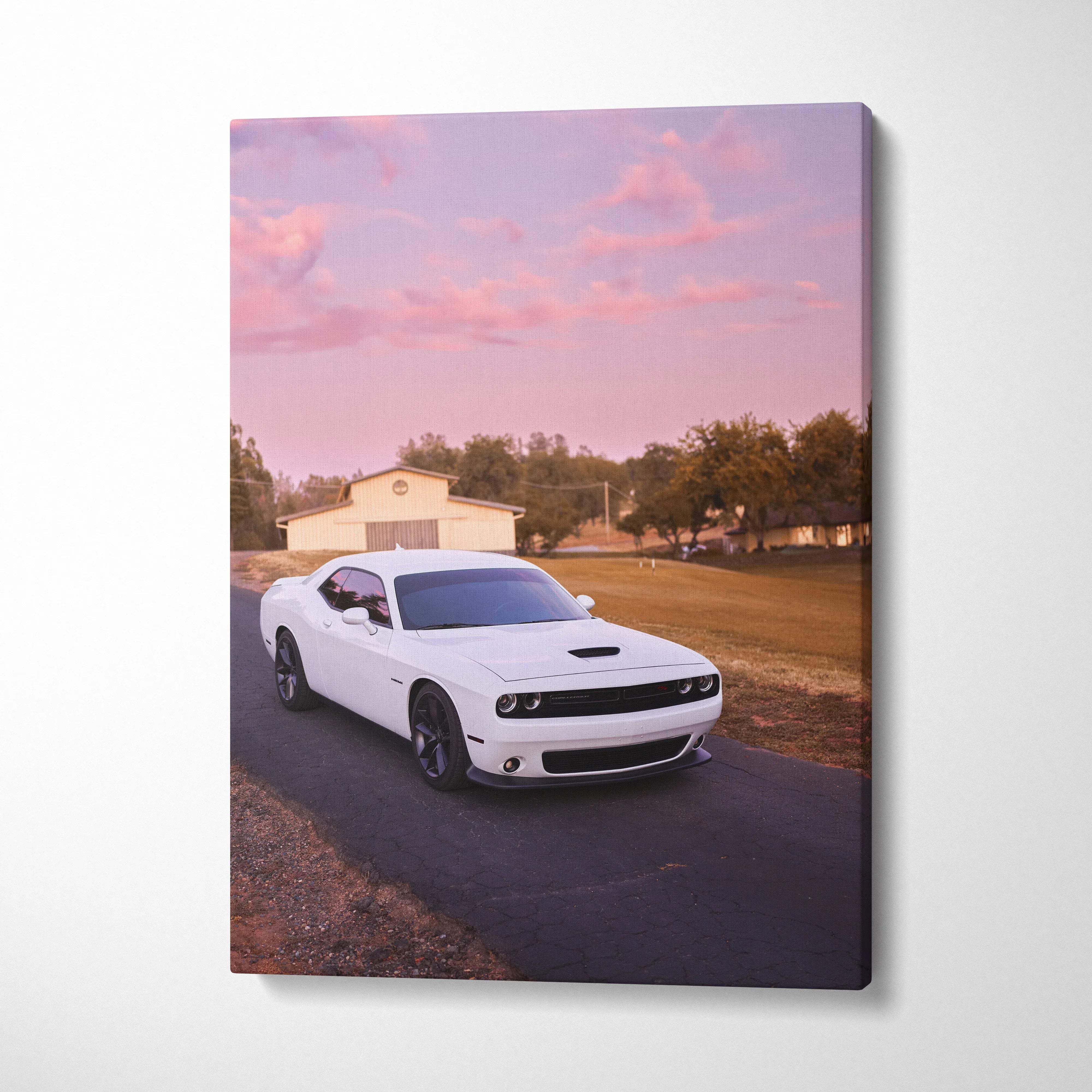 White Dodge Challenger on road at sunset with pink sky canvas wall art.
