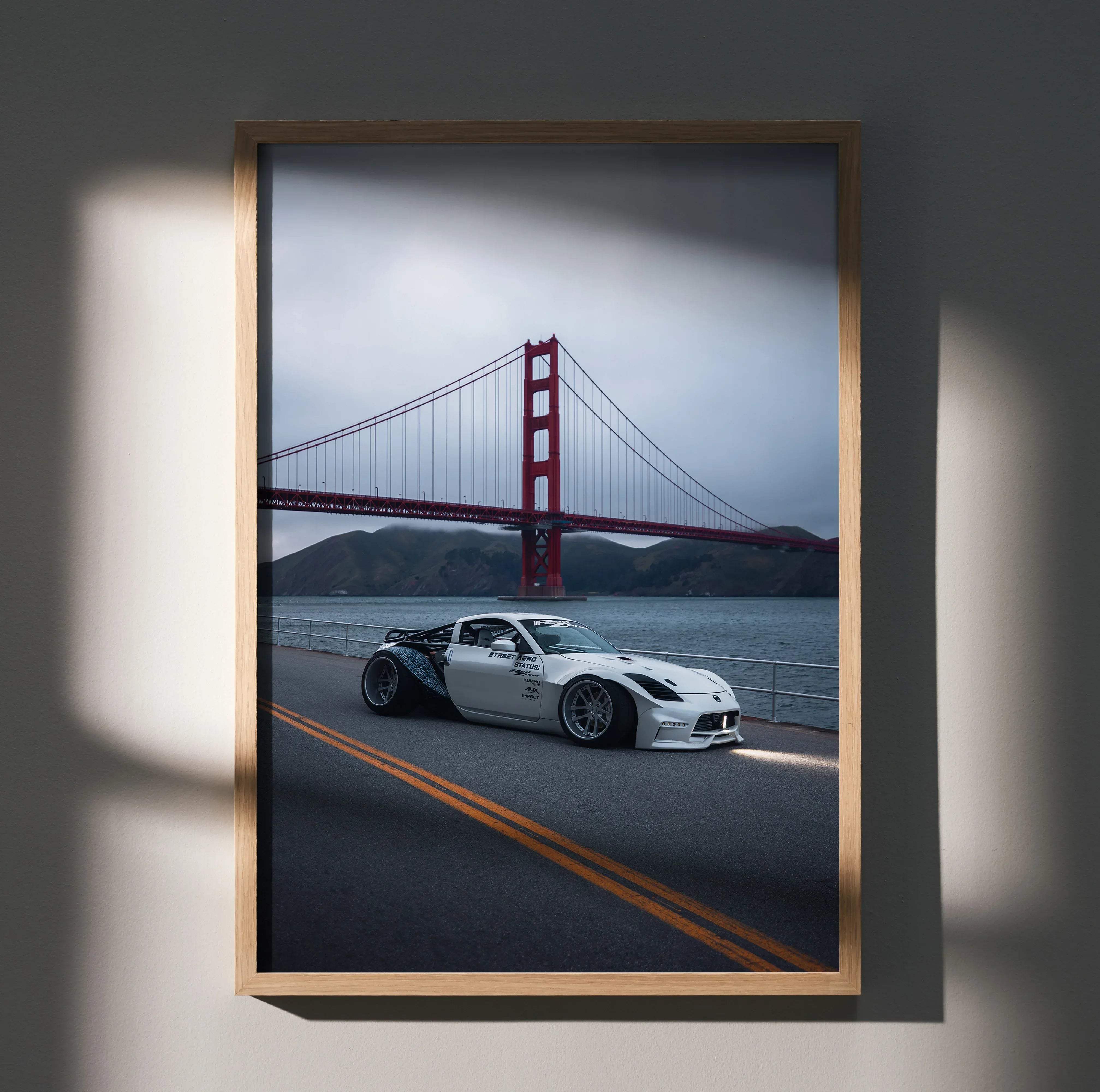 A framed high resolution nissan 350z widebody jdm car art poster featuring a white sports car by golden gate bridge