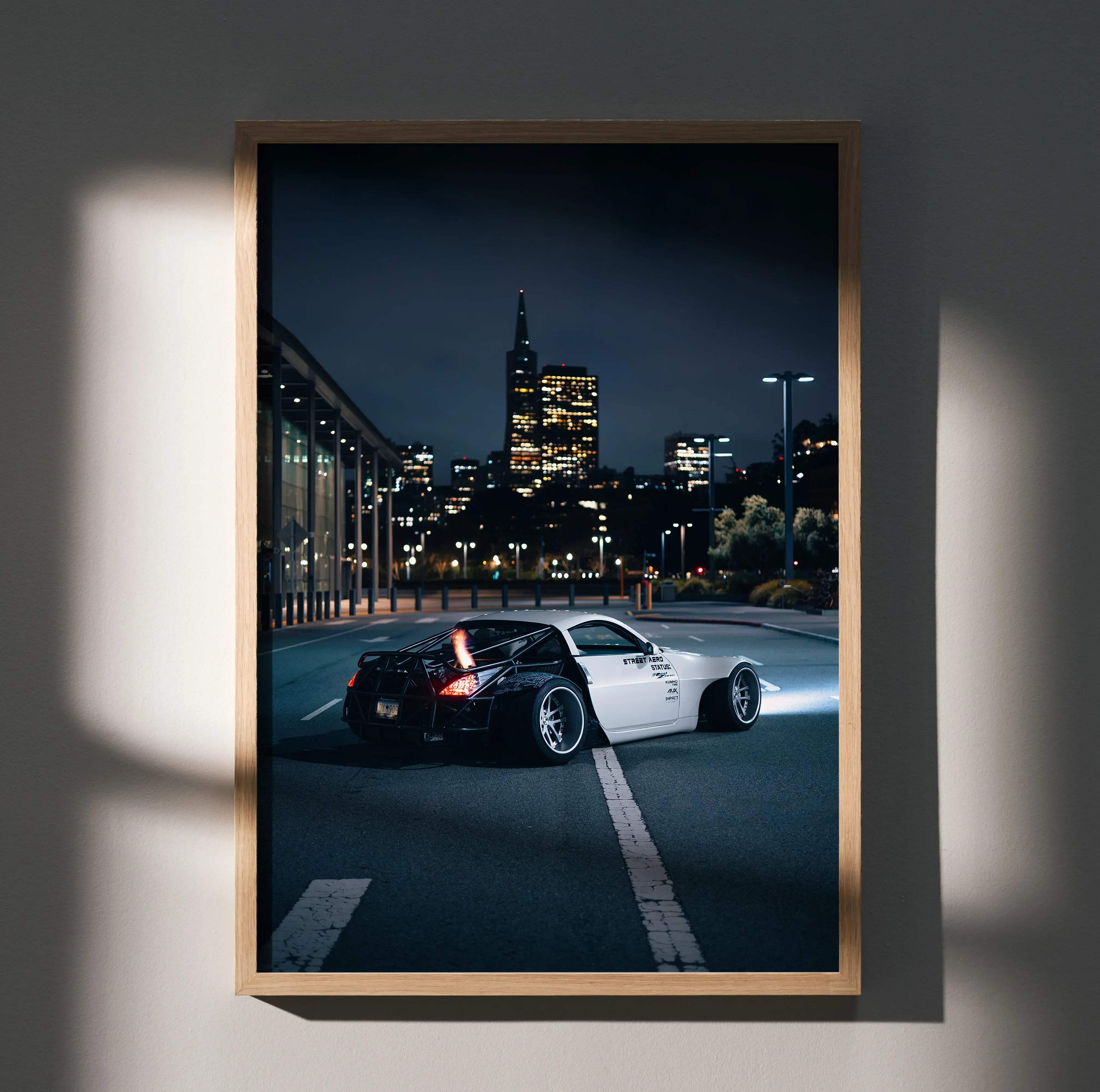 A framed Nissan 350z JDM widebody poster featuring a white sports car drifting at night in an urban setting