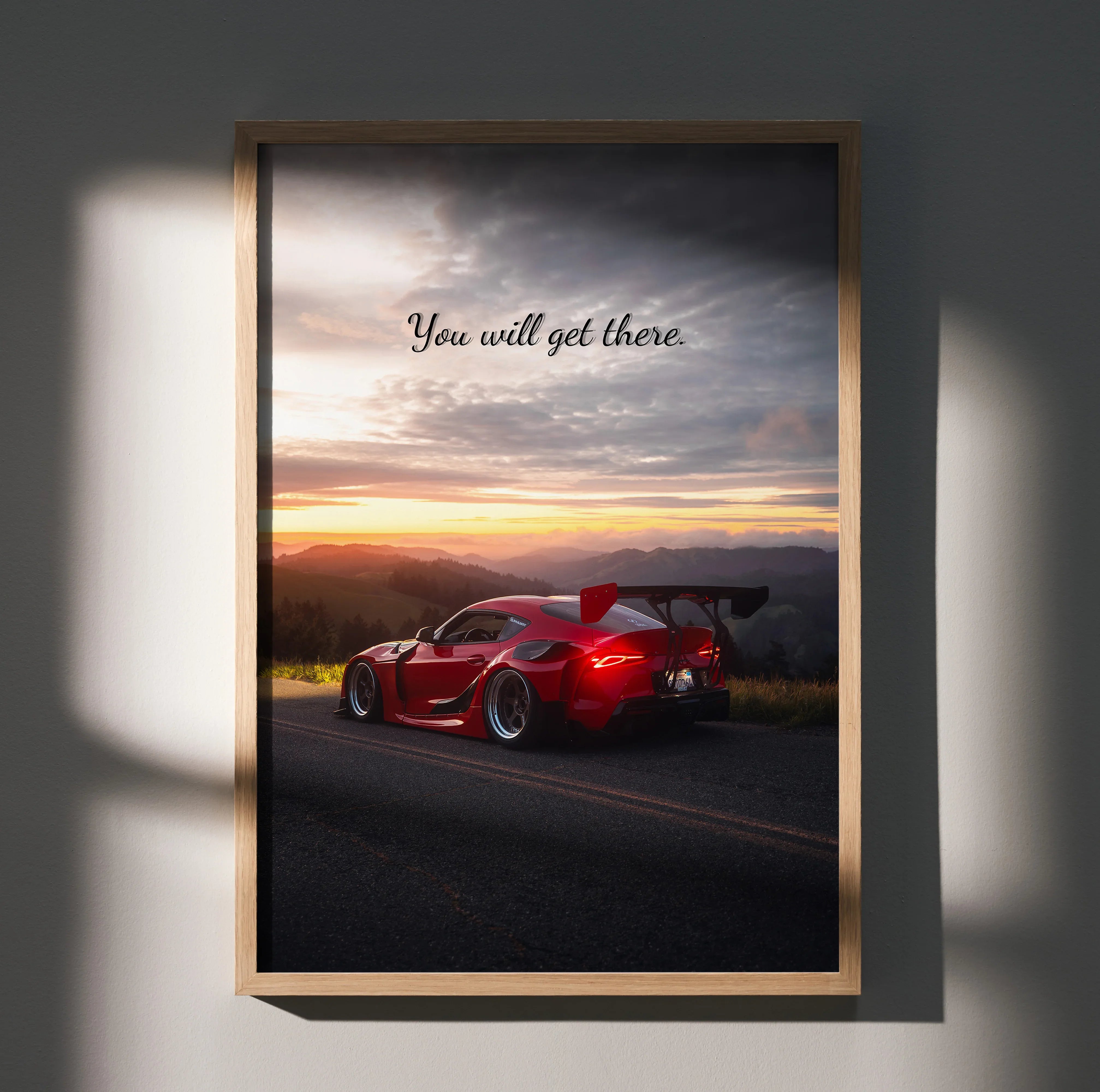 Motivational wall art poster featuring red Toyota Supra Mk5 on road at sunset with "You will get there" text.