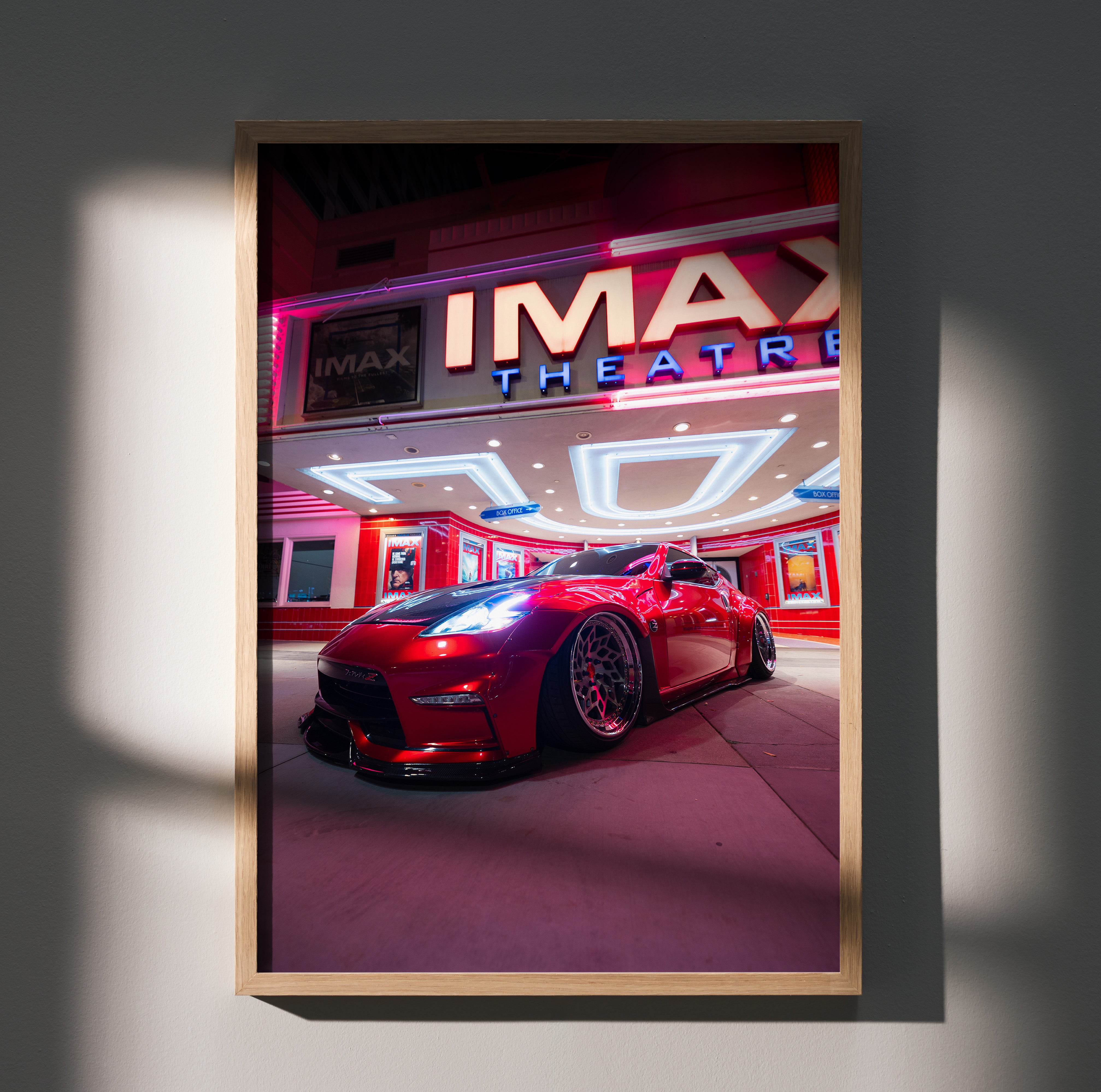Nissan 370z red sports car parked under bright IMAX Theater lights poster wall art.