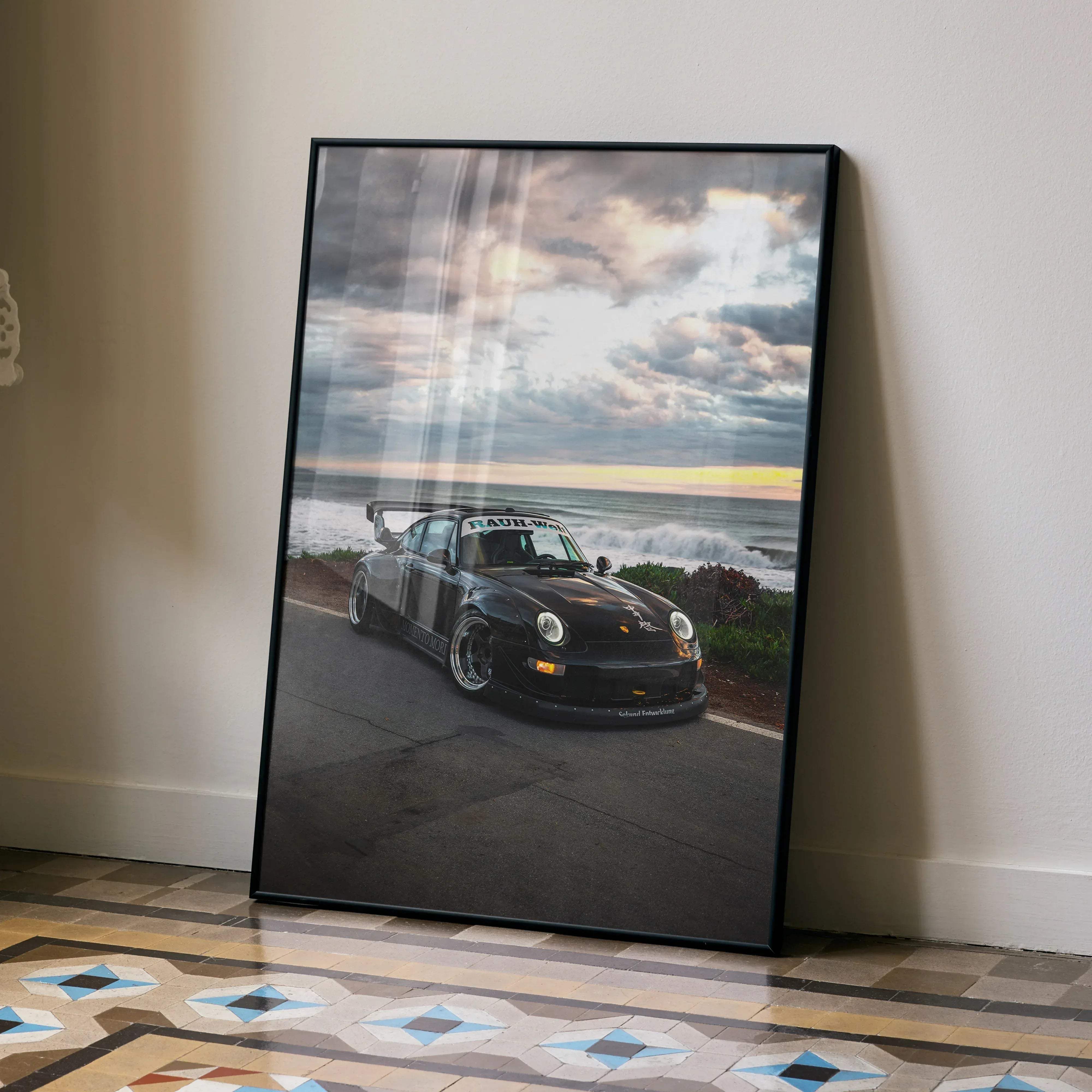 Black framed high-quality art print poster of a rauh-welt modified porsche 911 on coastal road under dramatic clouds