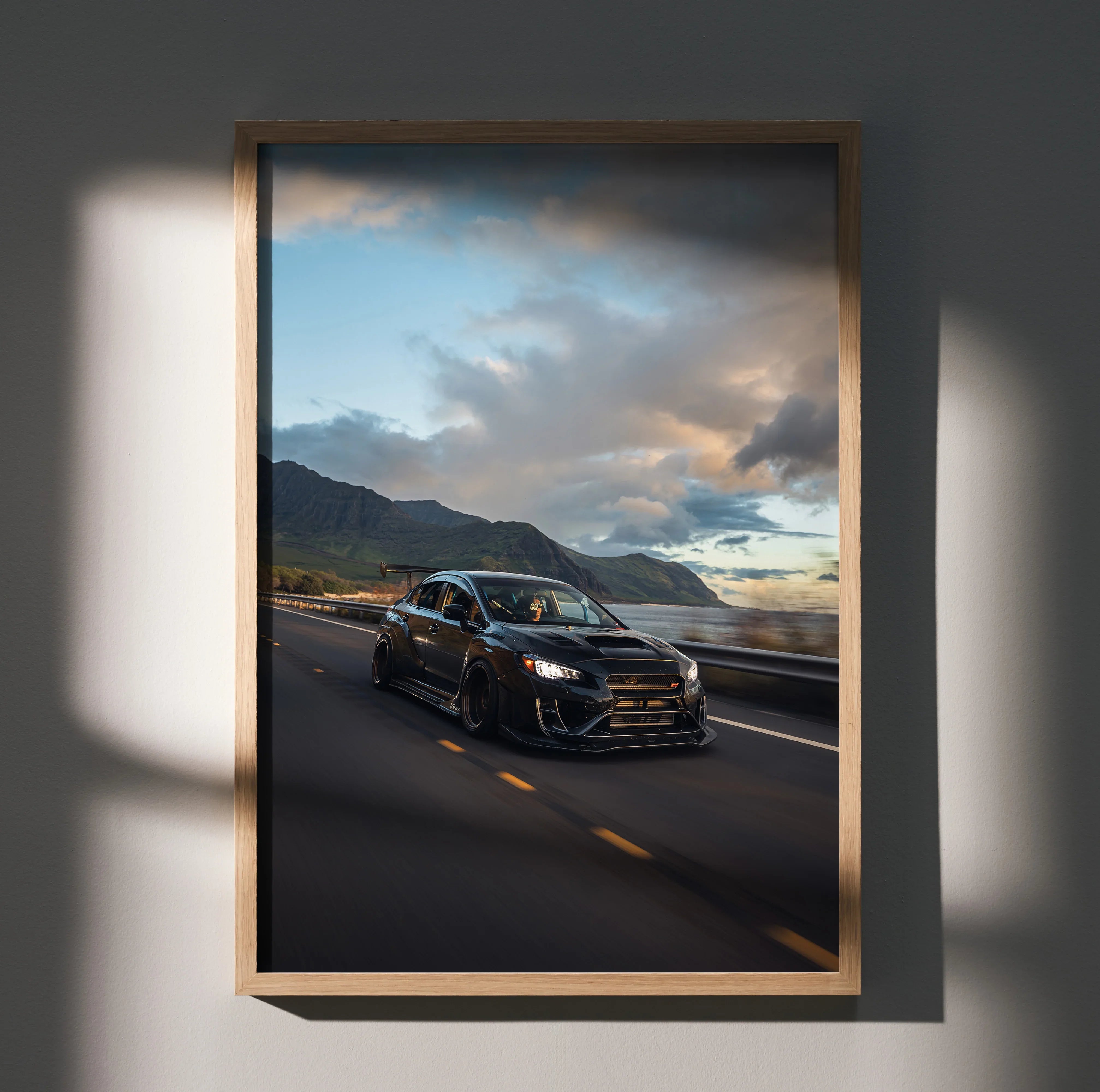 Subaru WRX STI driving on mountain road at sunset premium wall art poster in wooden frame.