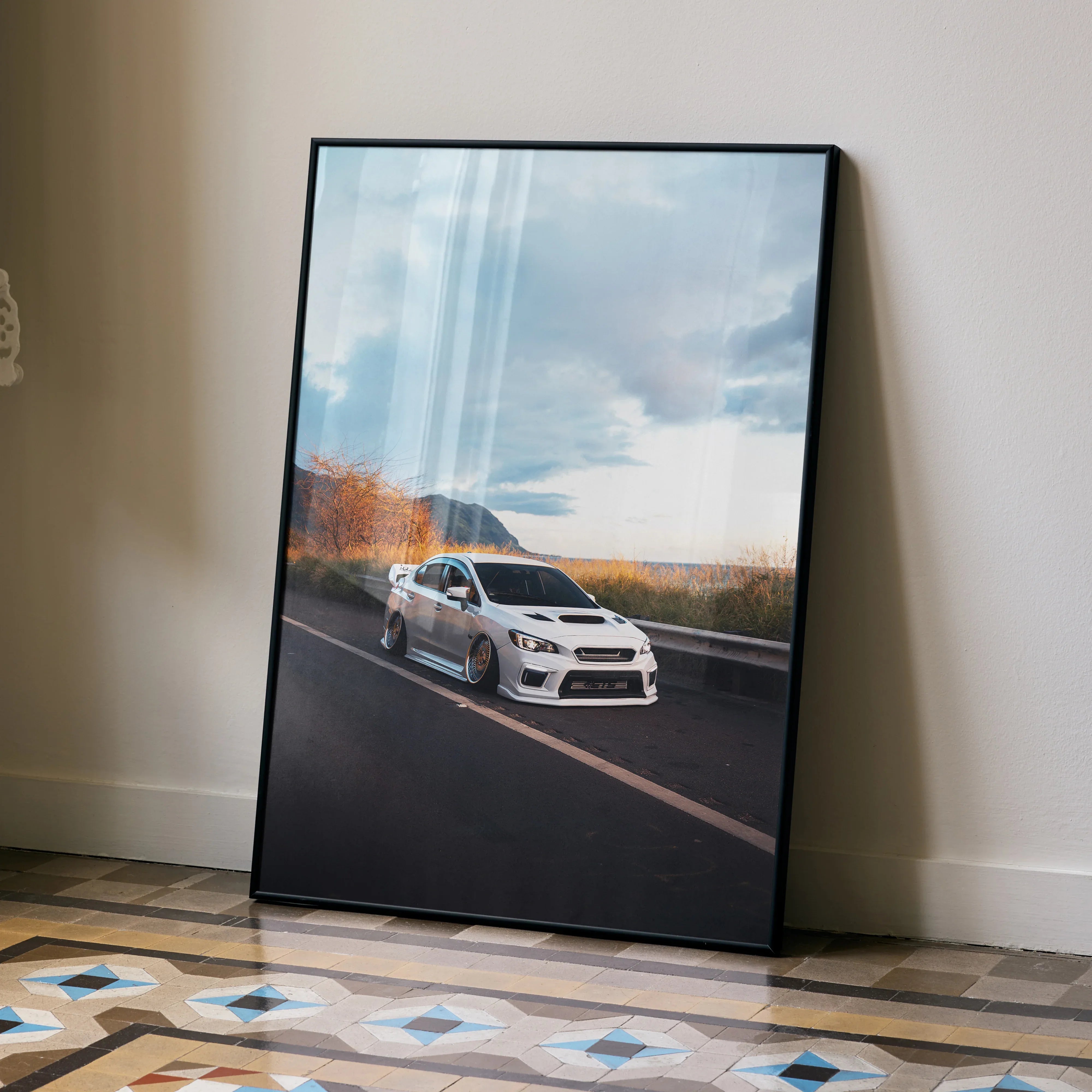 Slammed Subaru WRX driving on scenic road poster wall art with cloudy sky backdrop.