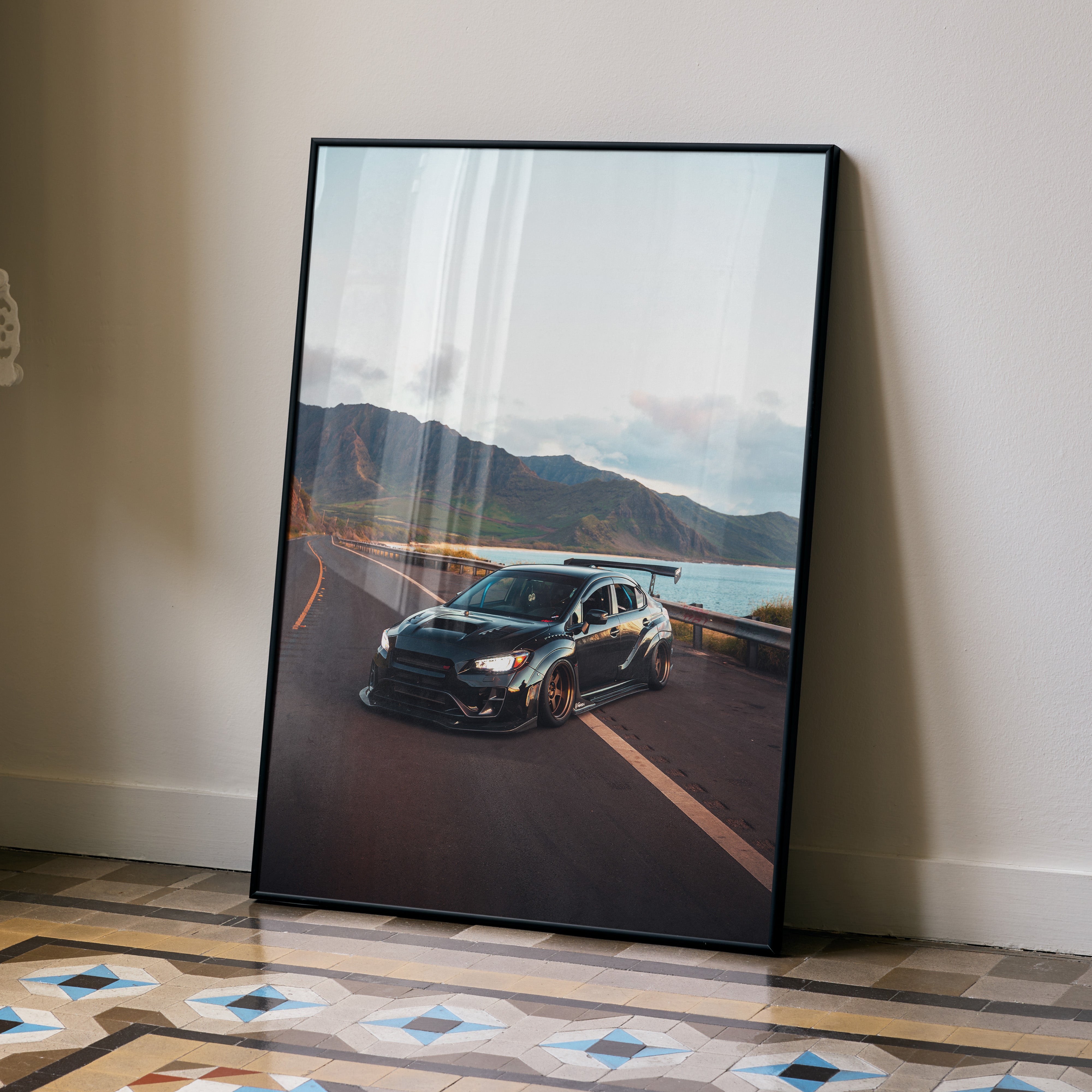 Subaru WRX STI black sports car on coastal road poster wall art with mountain background.