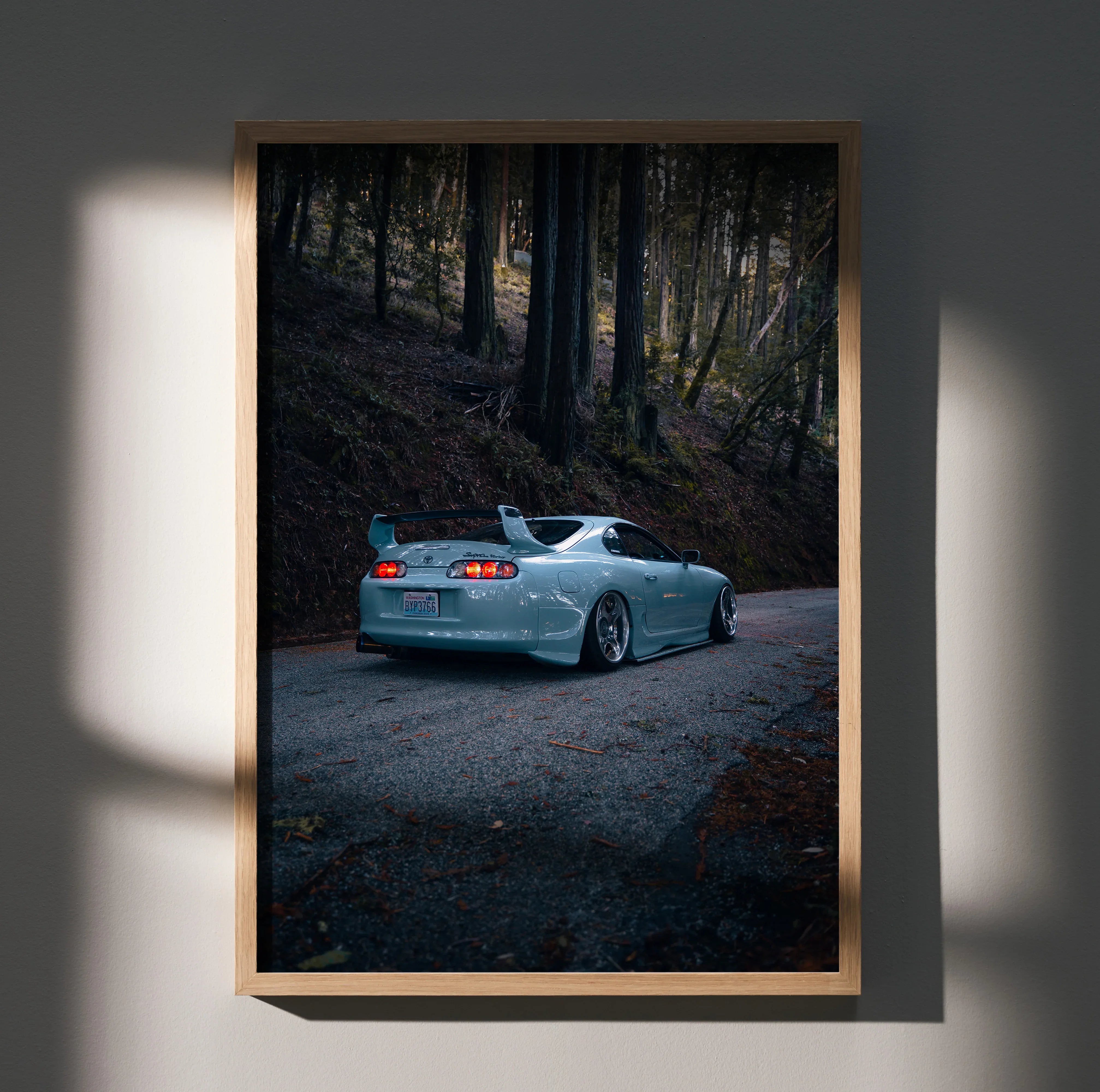 Toyota Supra Mk4 in dark forest setting poster wall art with sleek silver car and moody lighting.