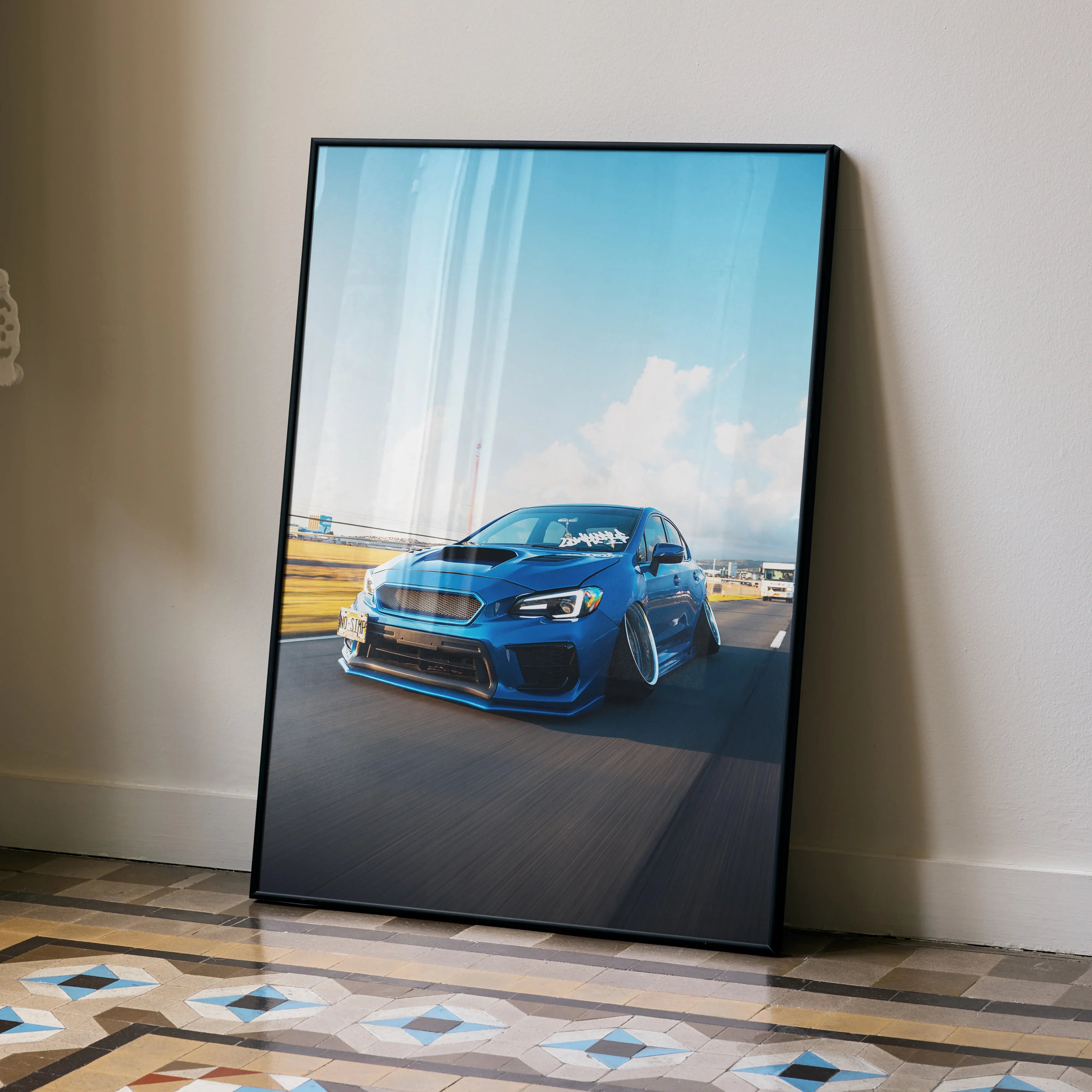 Slammed blue Subaru WRX poster leaning against wall with scenic sky backdrop wall art.