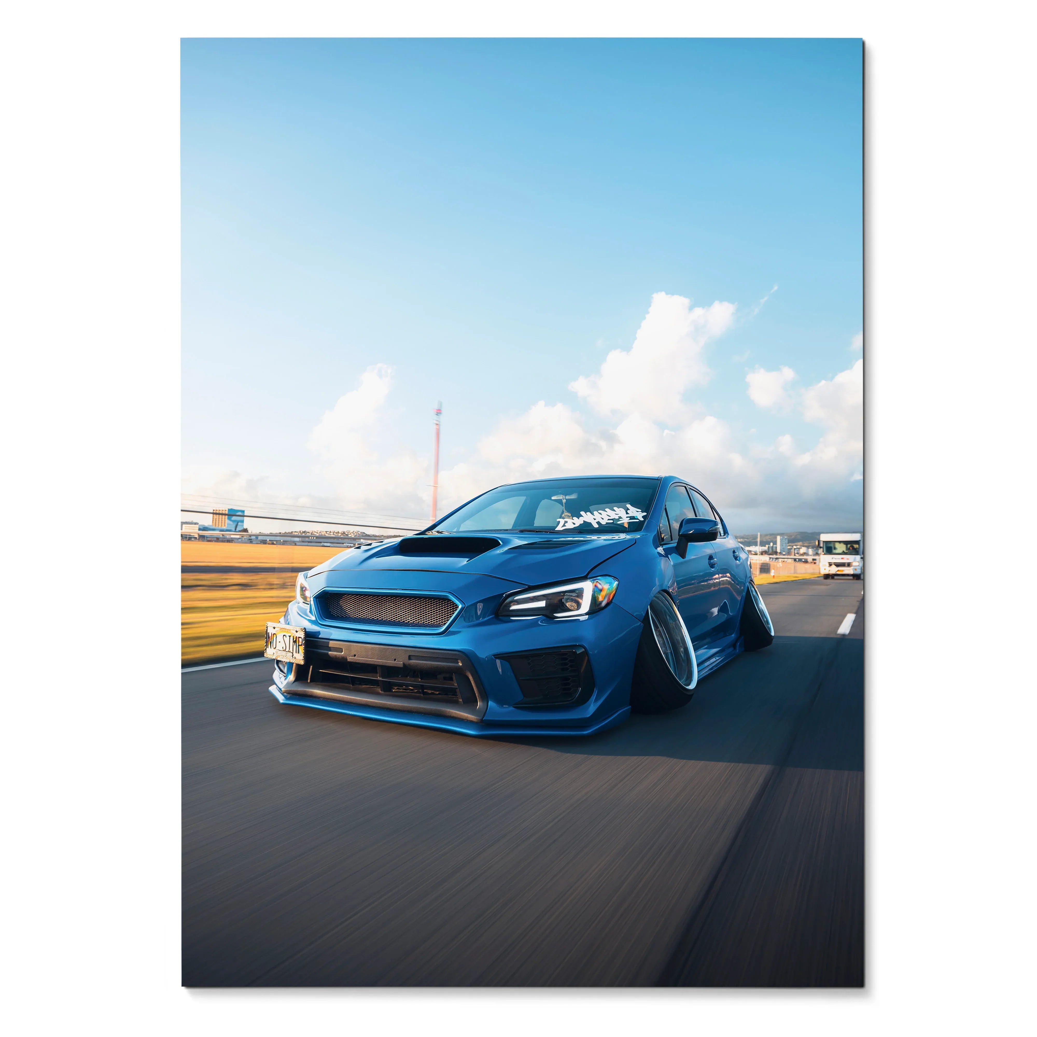 Blue slammed Subaru WRX driving on road poster wall art with clear sky background.