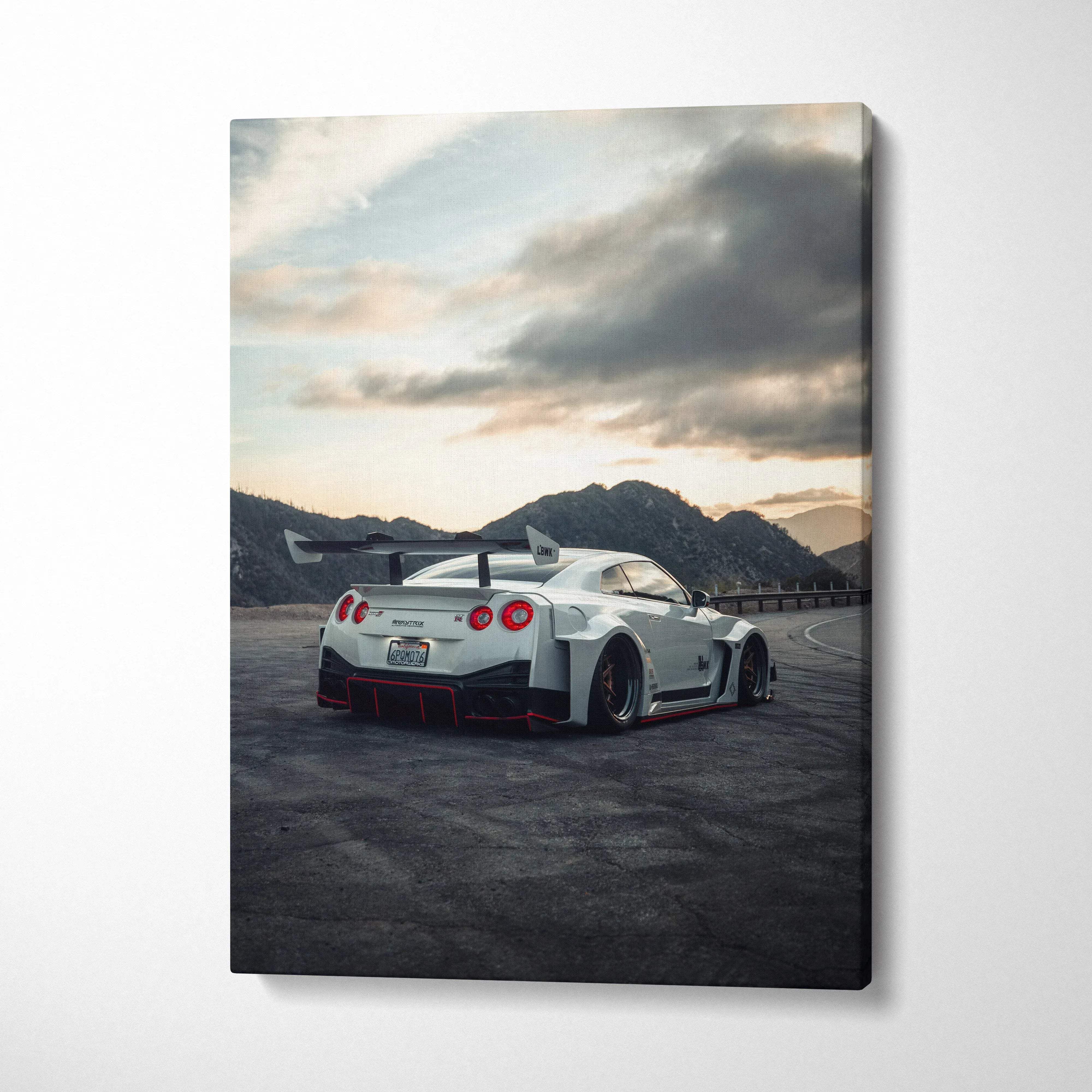 Vertical canvas wall art featuring a white Nissan R35 GTR sports car at sunset with mountainous background.
