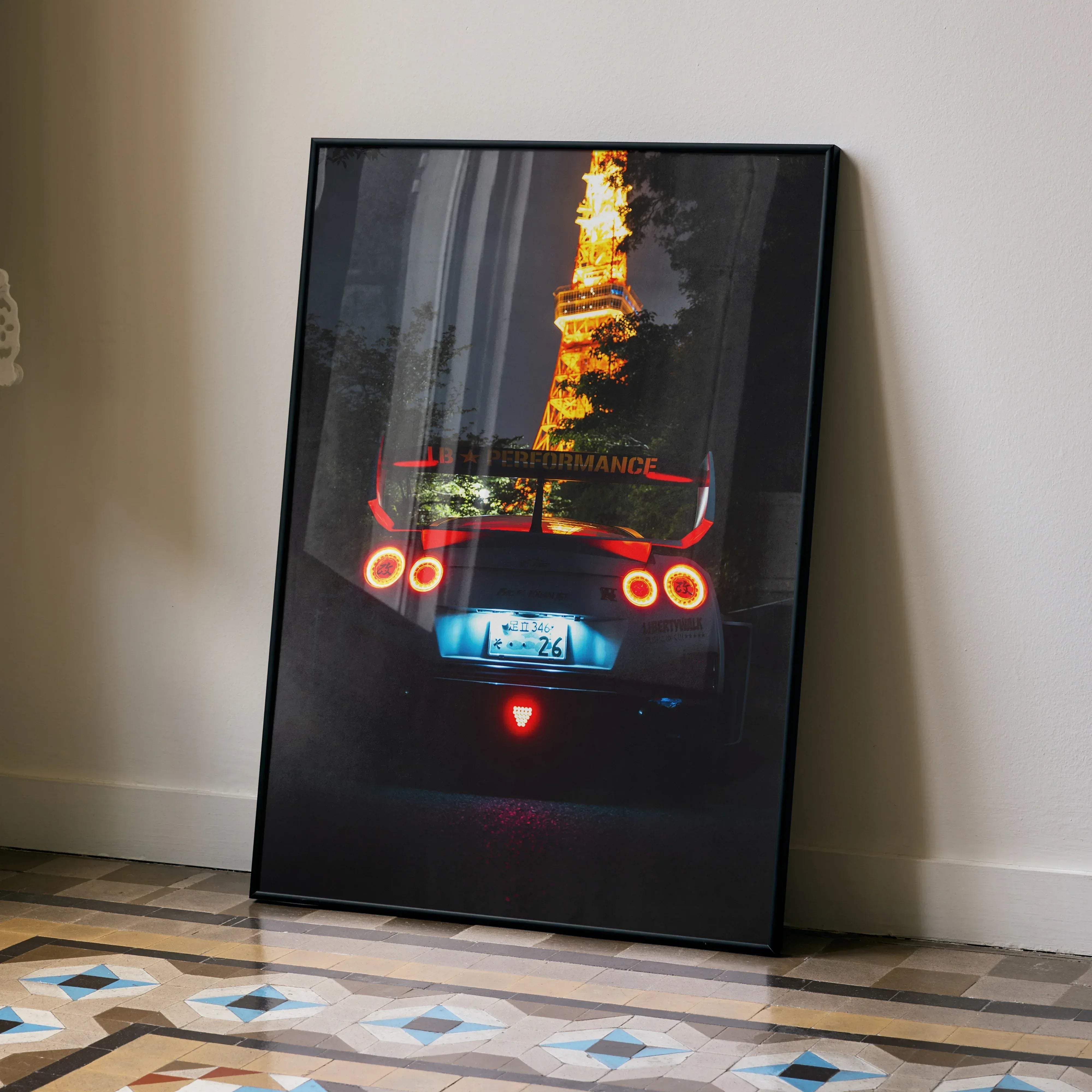Black-framed artwork showing a glowing eiffel tower behind the rear view of a red nissan gt-r r35 with taillights illuminated