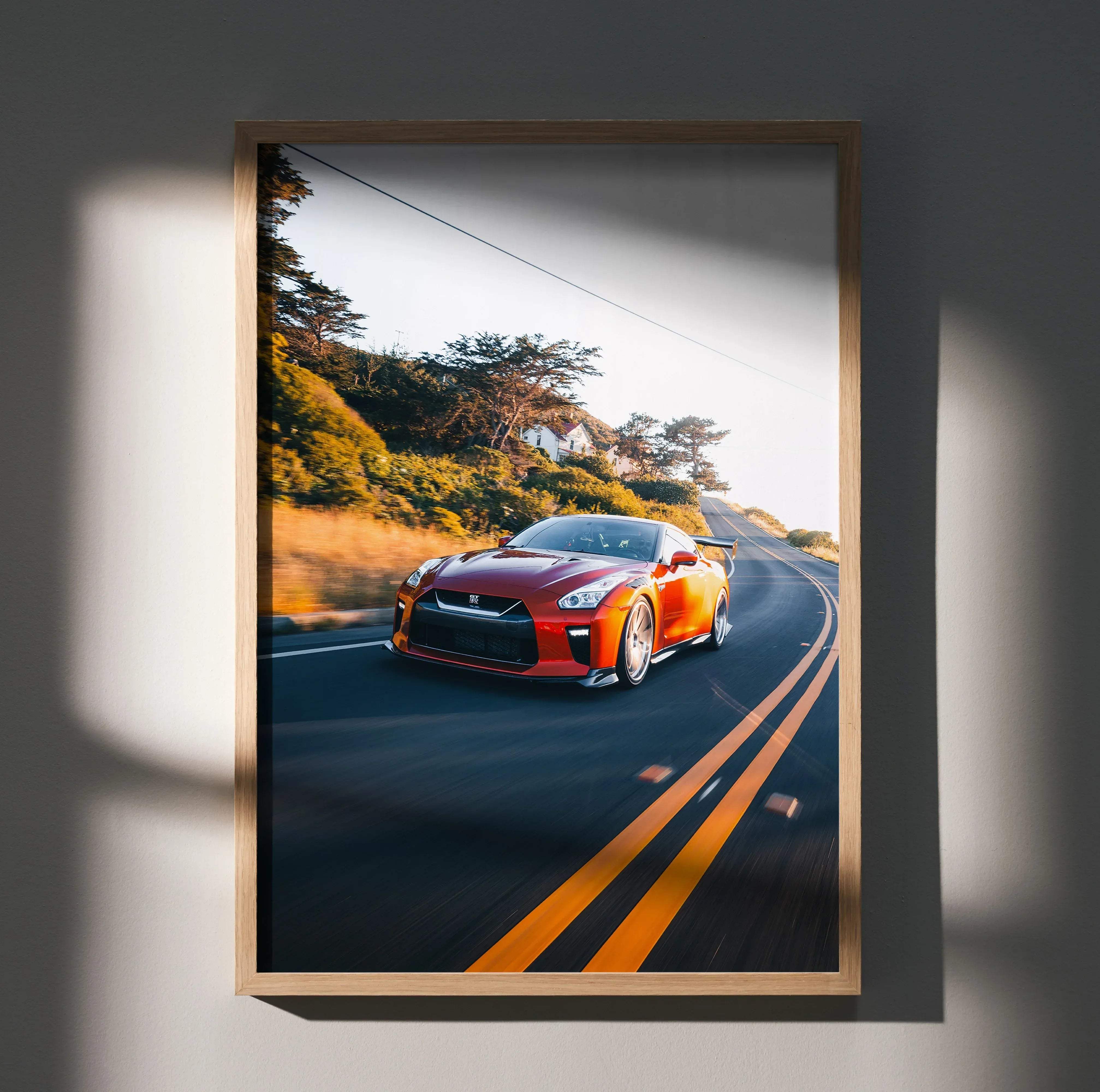 Nissan r35 gtr art print #026 featuring a vibrant red gt-r speeding on a coastal road in a light wooden frame
