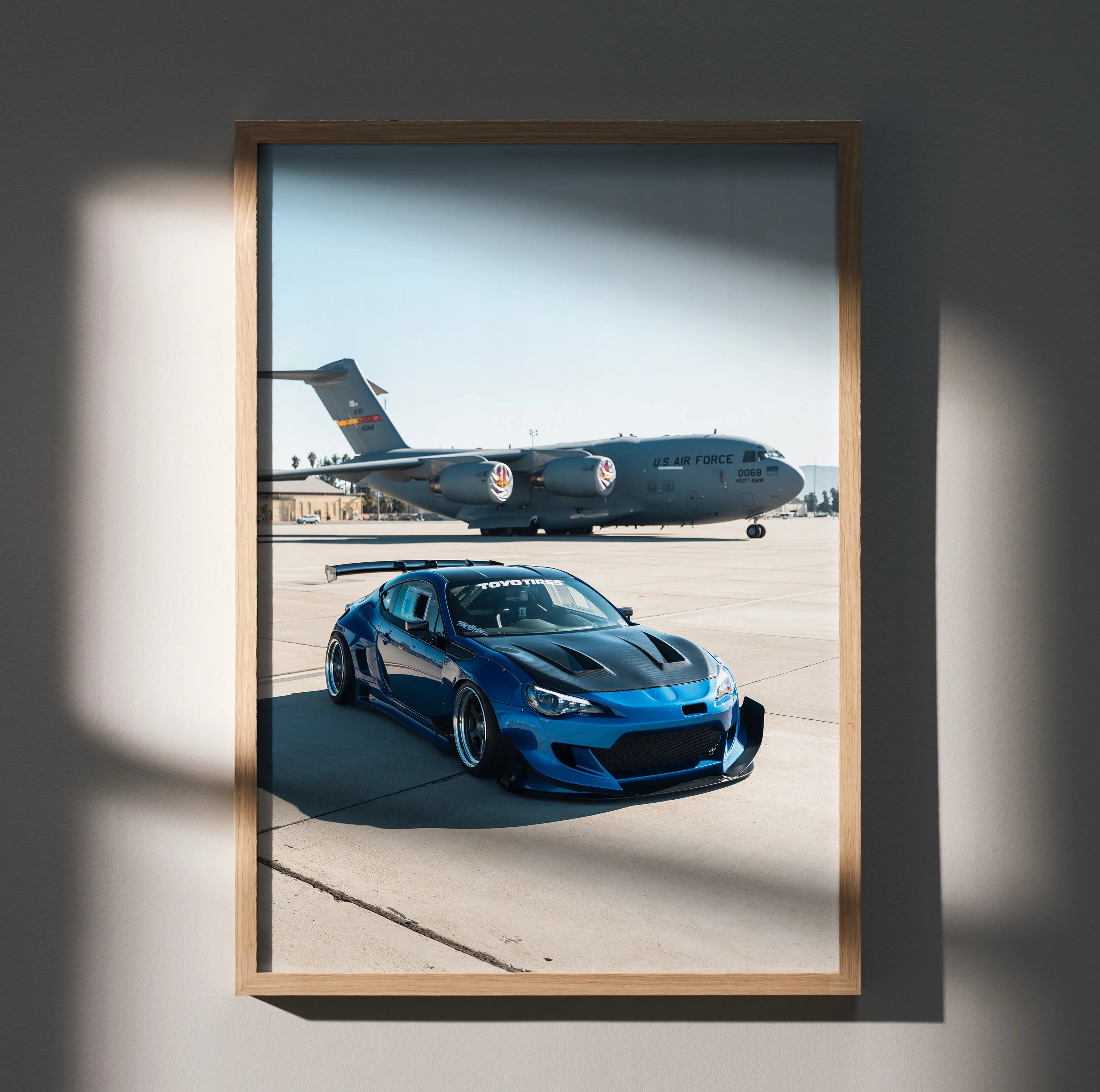 Blue Toyota FRS car poster with military airplane background, framed wall art in natural light.