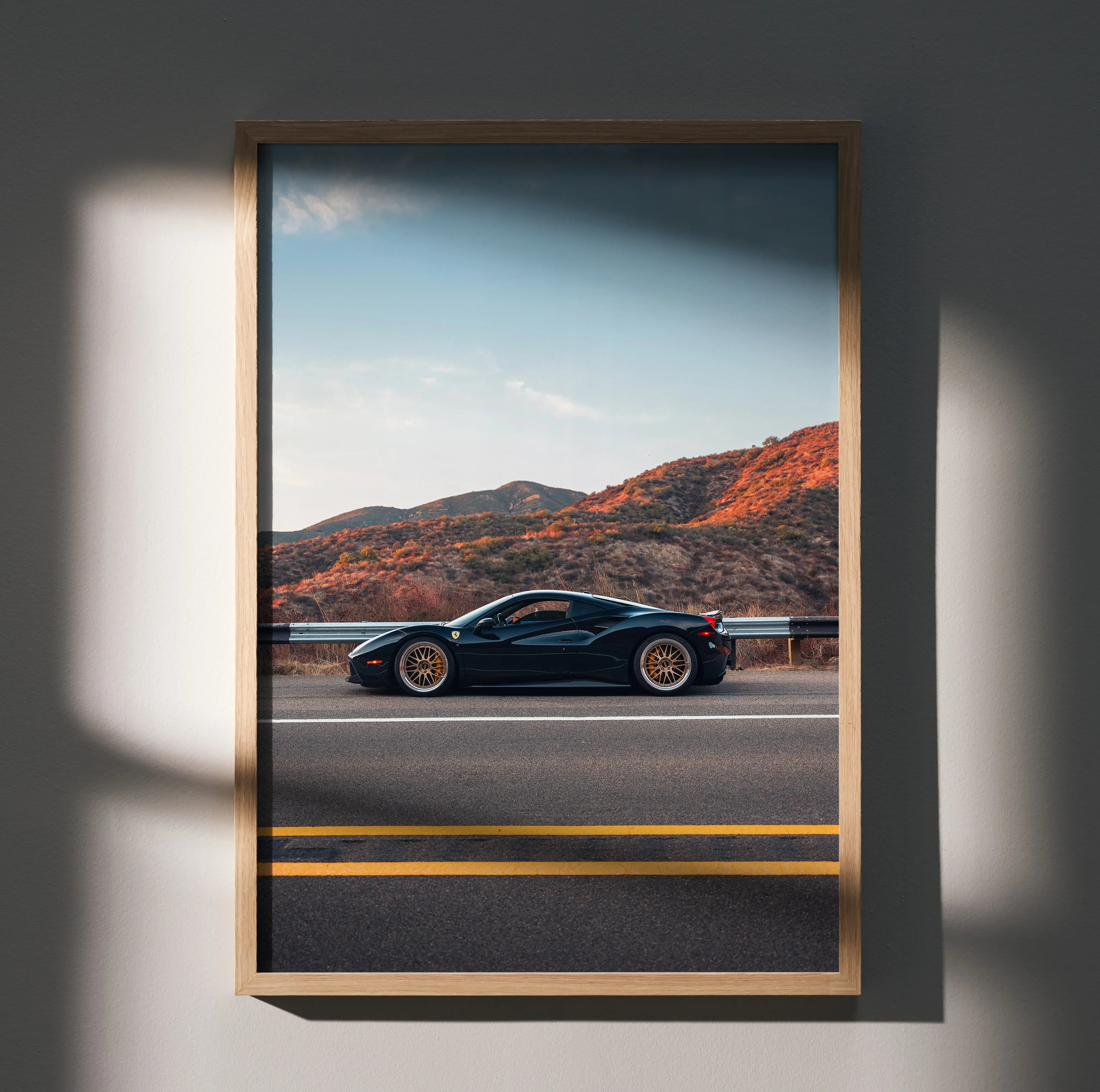 Sleek black Ferrari 488 GTB poster with orange wheels on desert road, wall art in natural light.