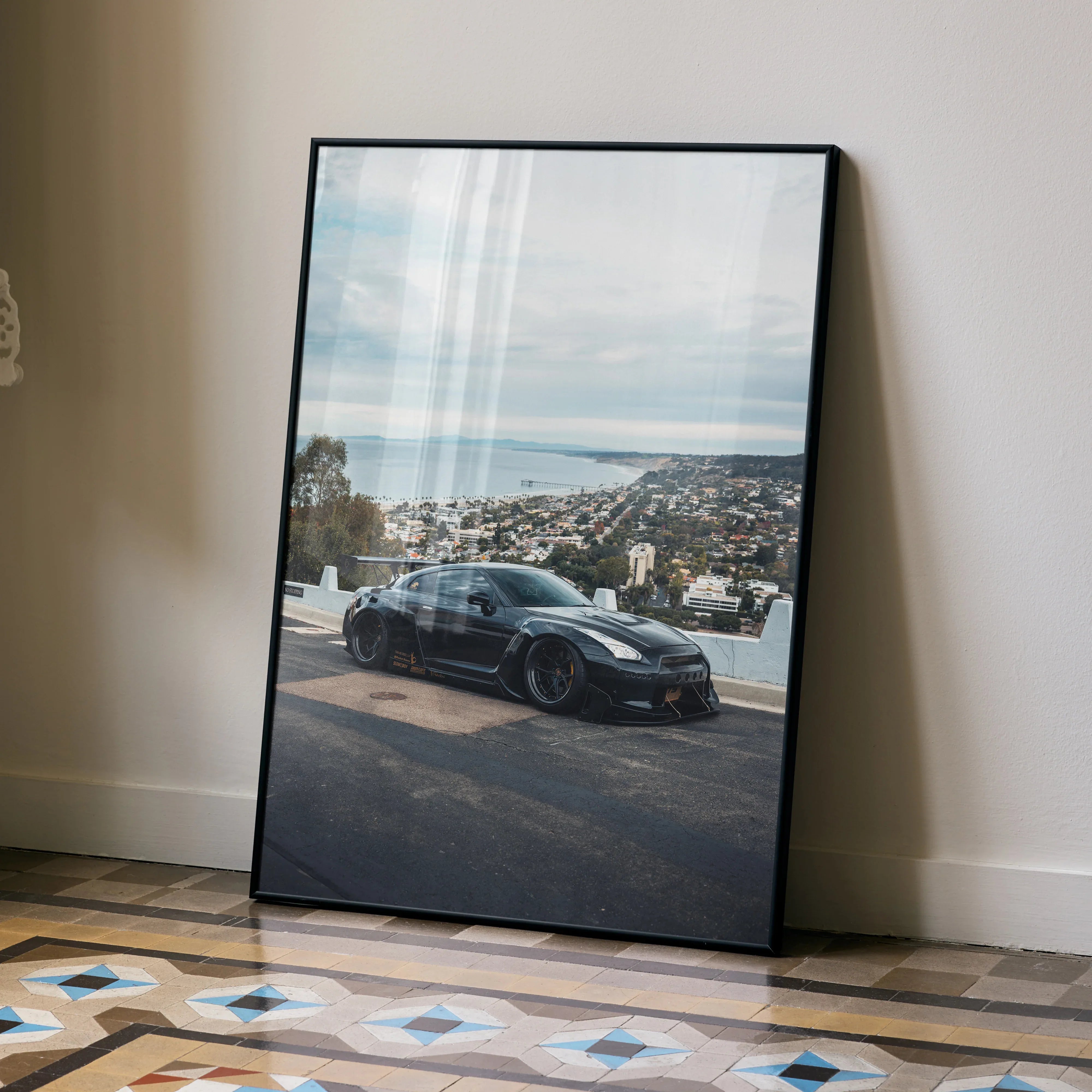 Nissan R35 GTR poster wall art showing sleek black sports car with cityscape background.