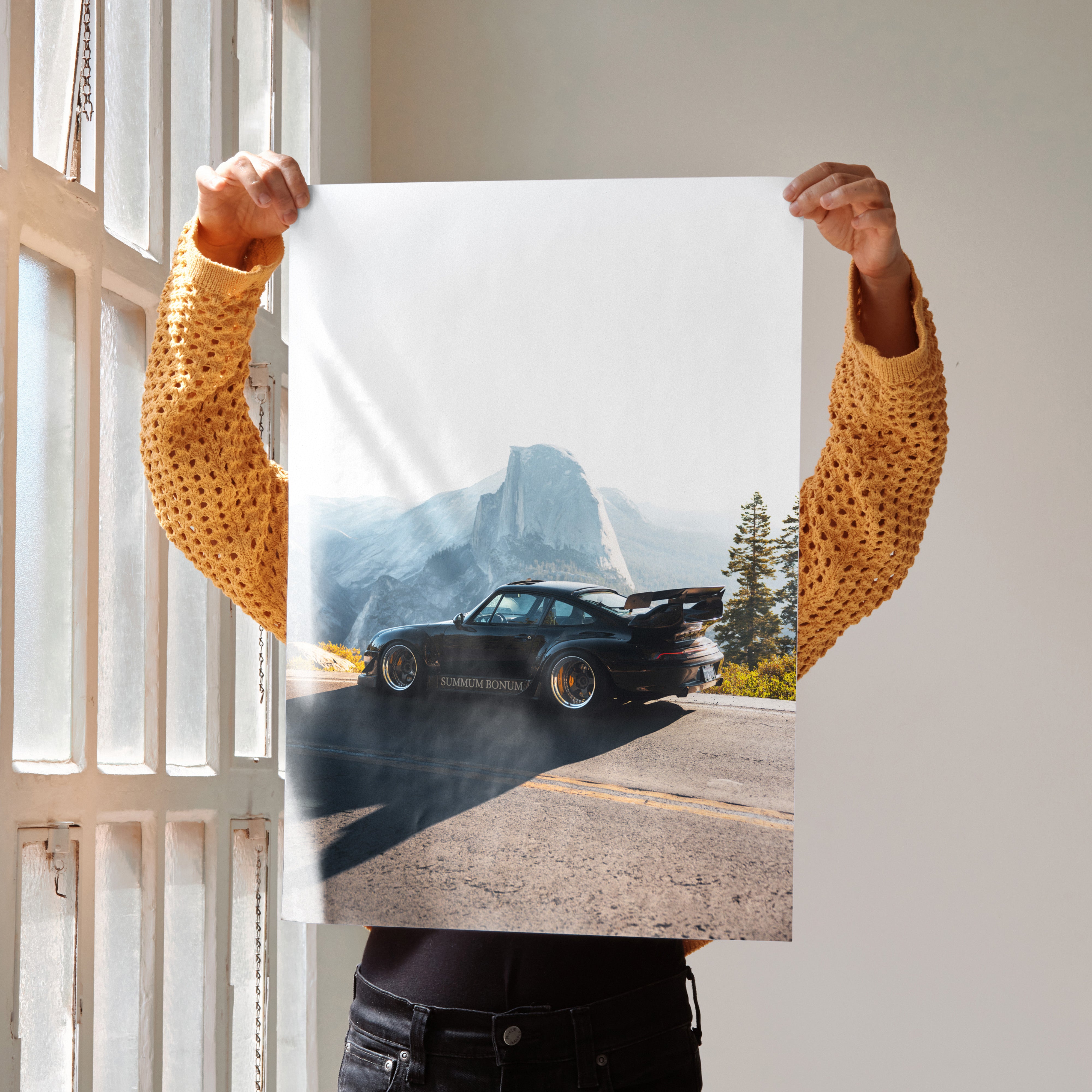 Poster of black RWB Porsche 911 on sunlit road with mountain and trees background wall art.