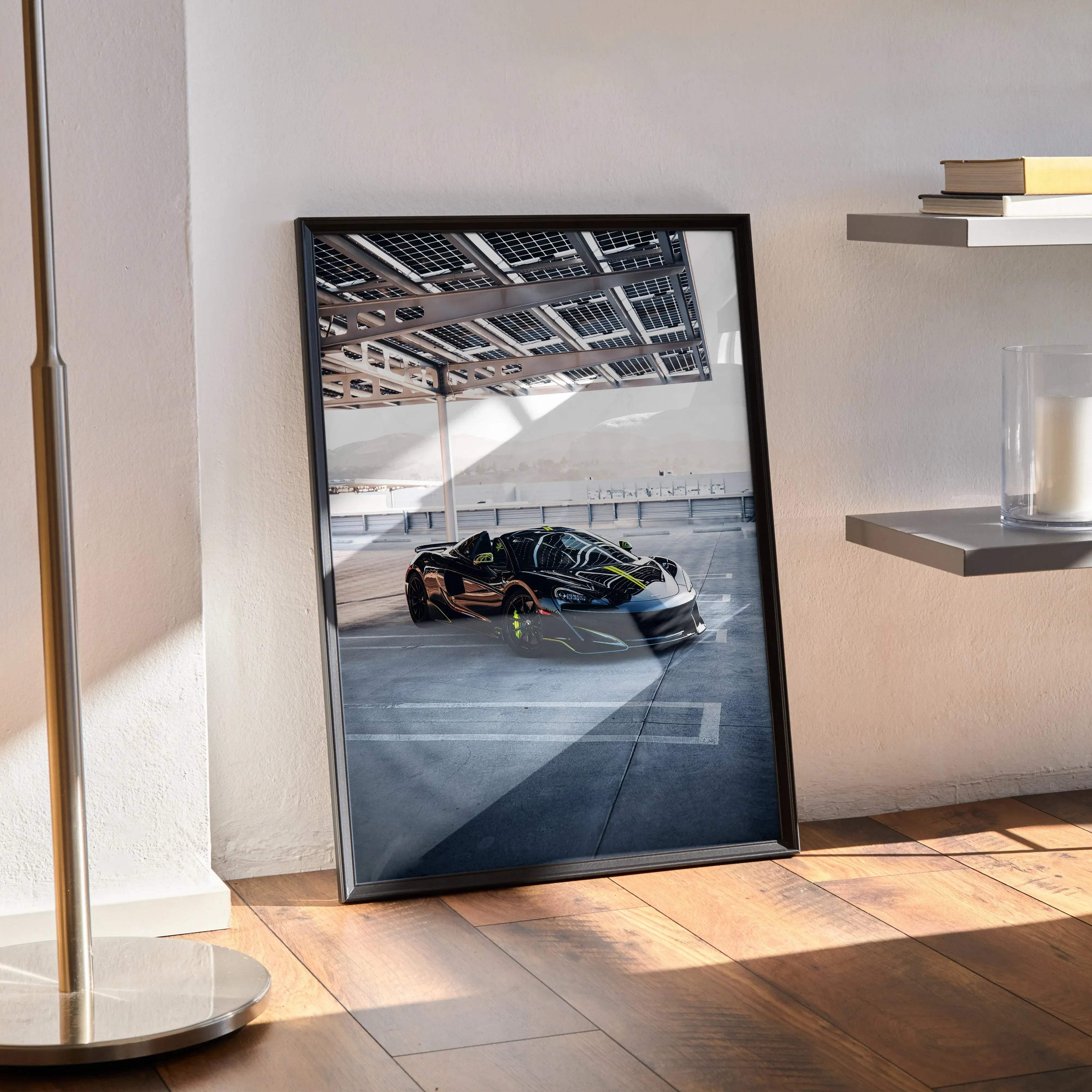 Black-framed art print of sleek glossy black and gold mclaren 600lt supercar under industrial roof for premium wall decor