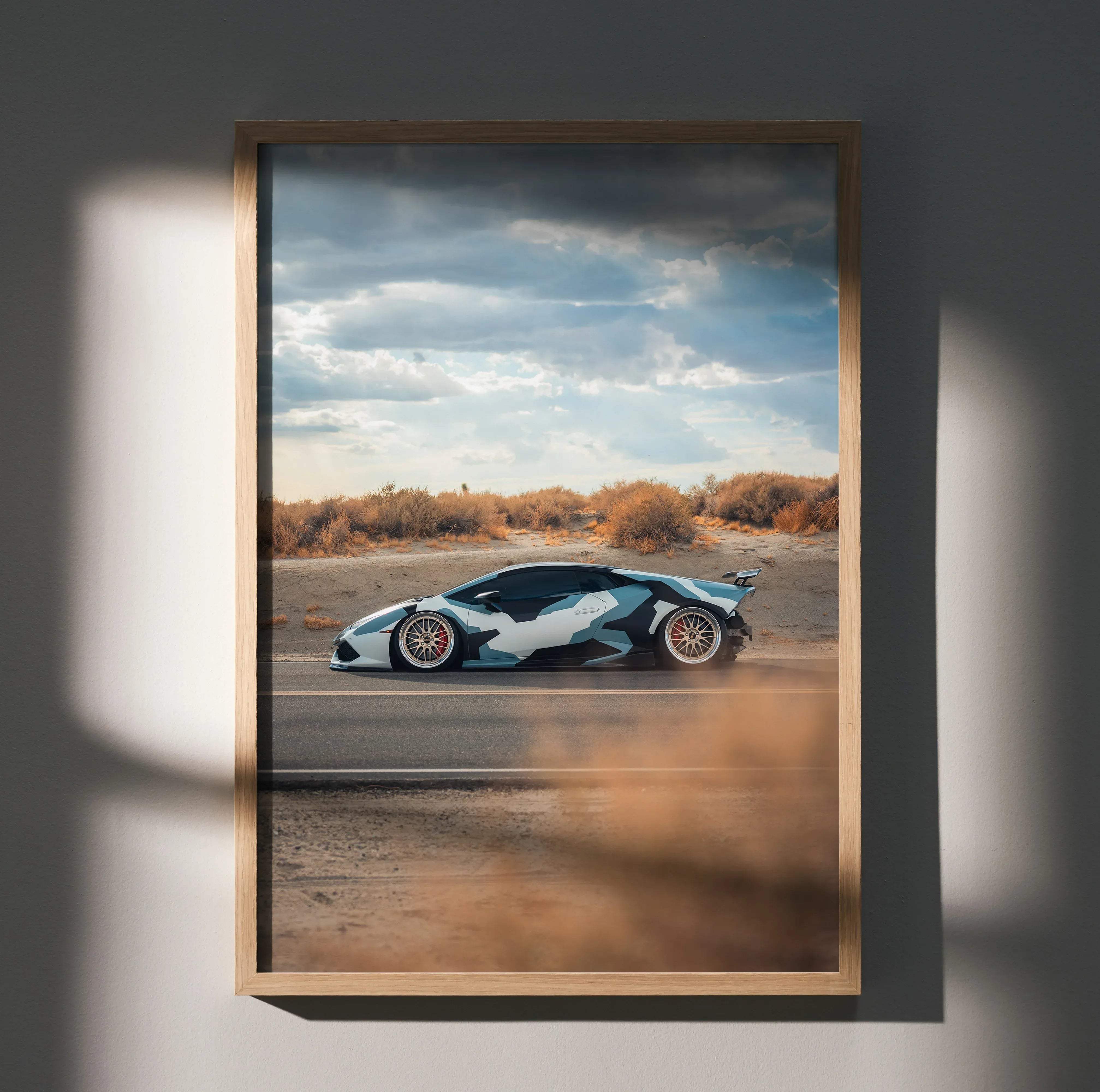 A framed Lamborghini Huracan high resolution car poster featuring a white and blue camouflage sports car on a desert road