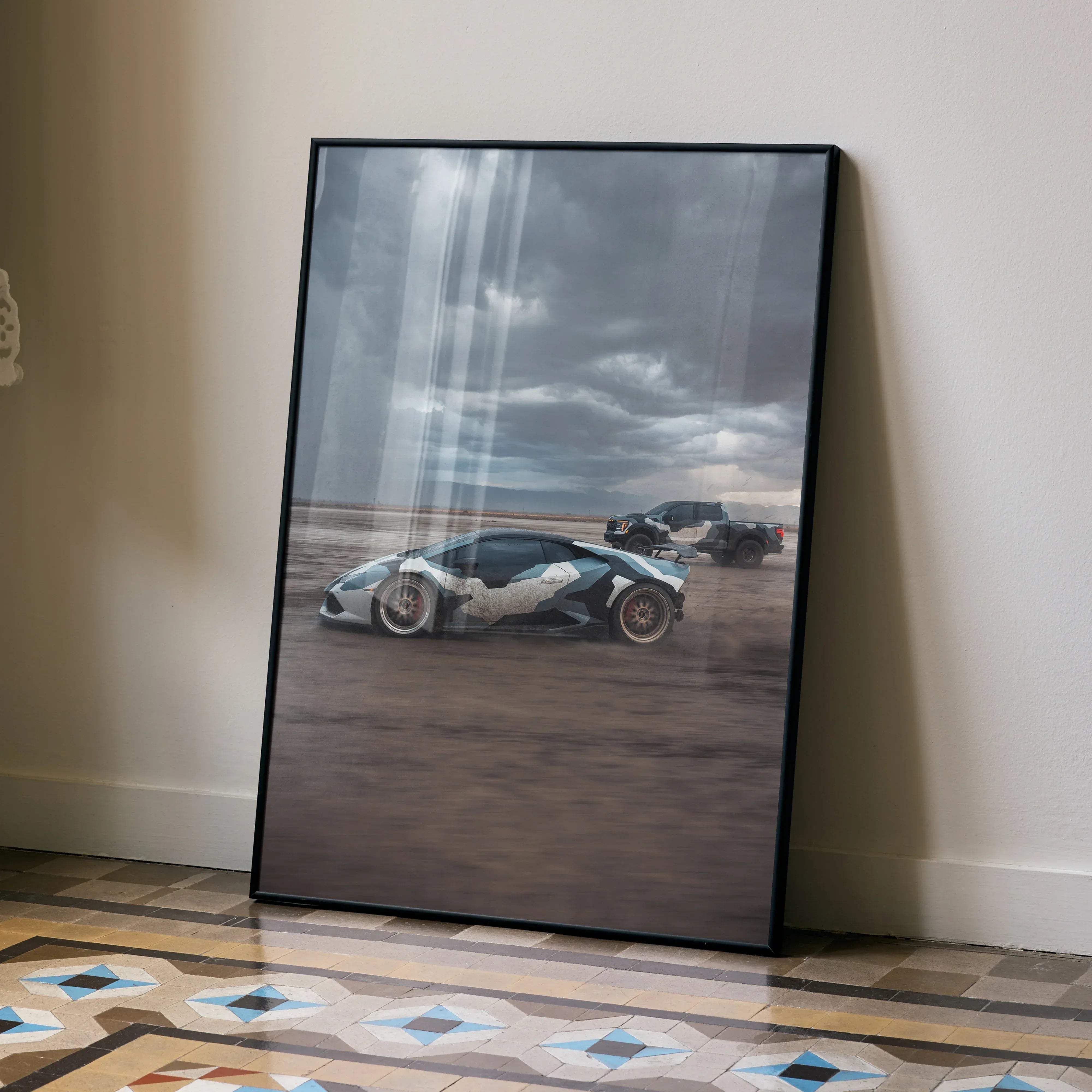Black-framed art print of white and gray lamborghini huracan with red accents on desert terrain under stormy skies