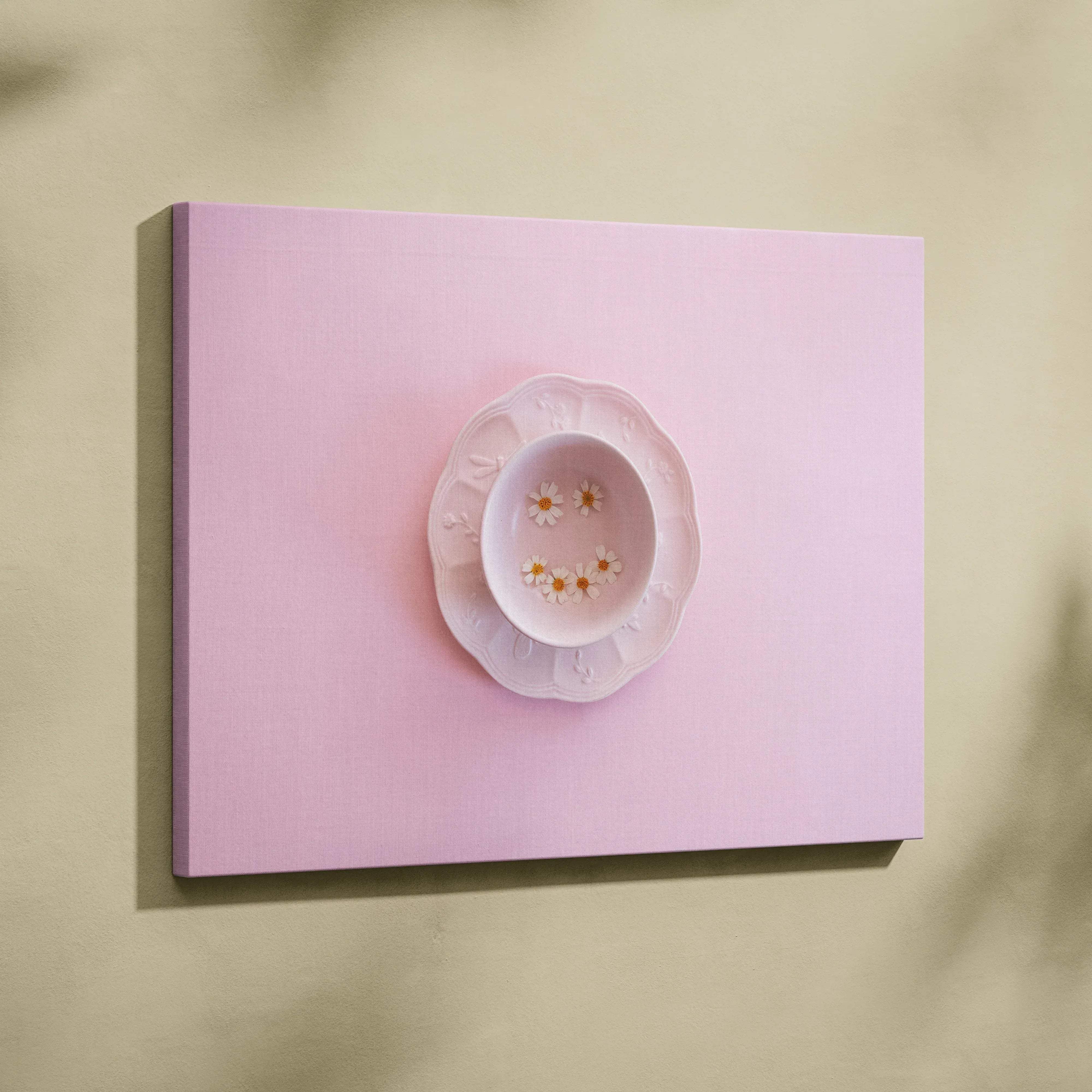 A delicate white porcelain teacup and saucer set with tiny daisies inside, styled with minimalist pink plate wall art