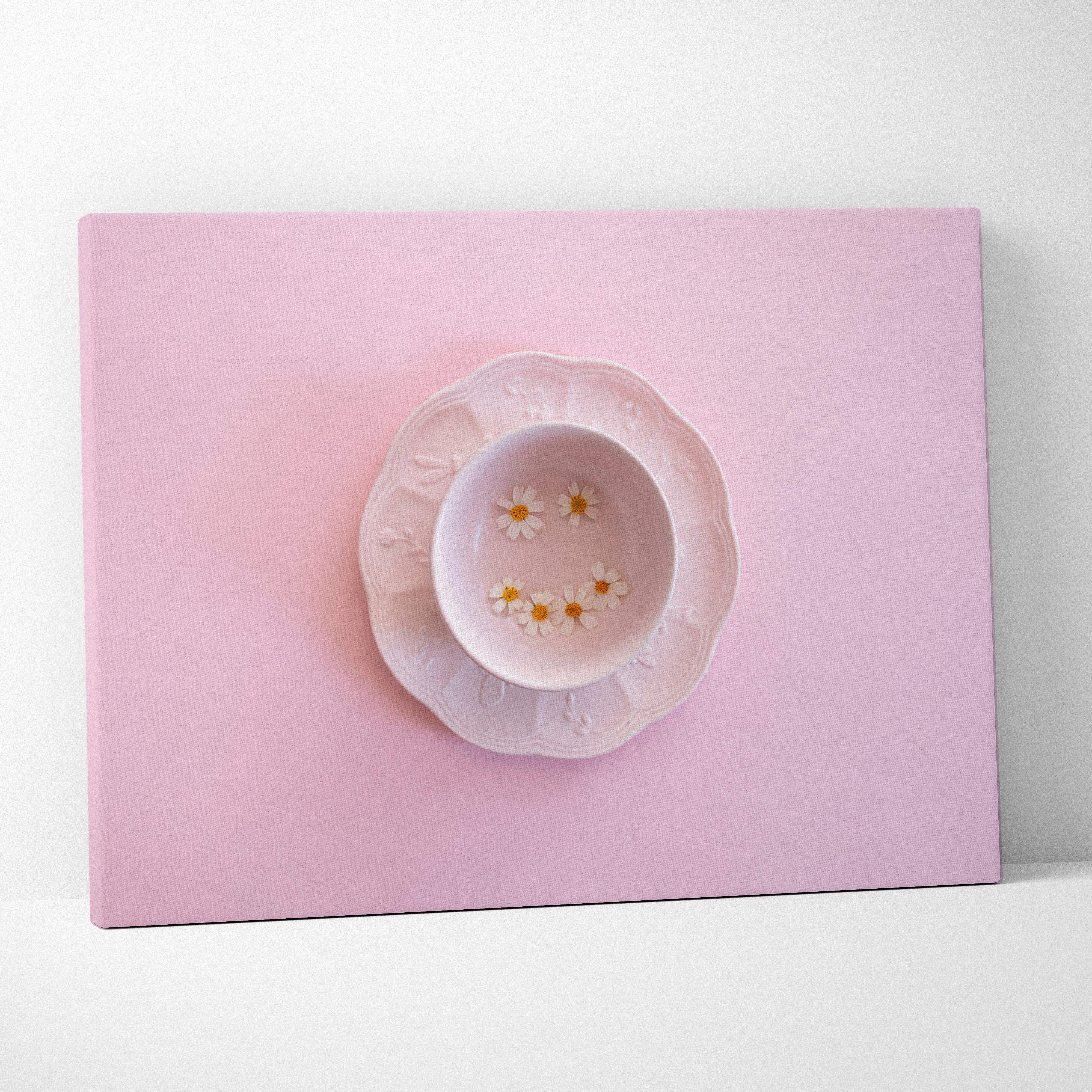 A delicate pink ceramic teacup and scalloped edge saucer set paired with minimalist pink daisy canvas wall art