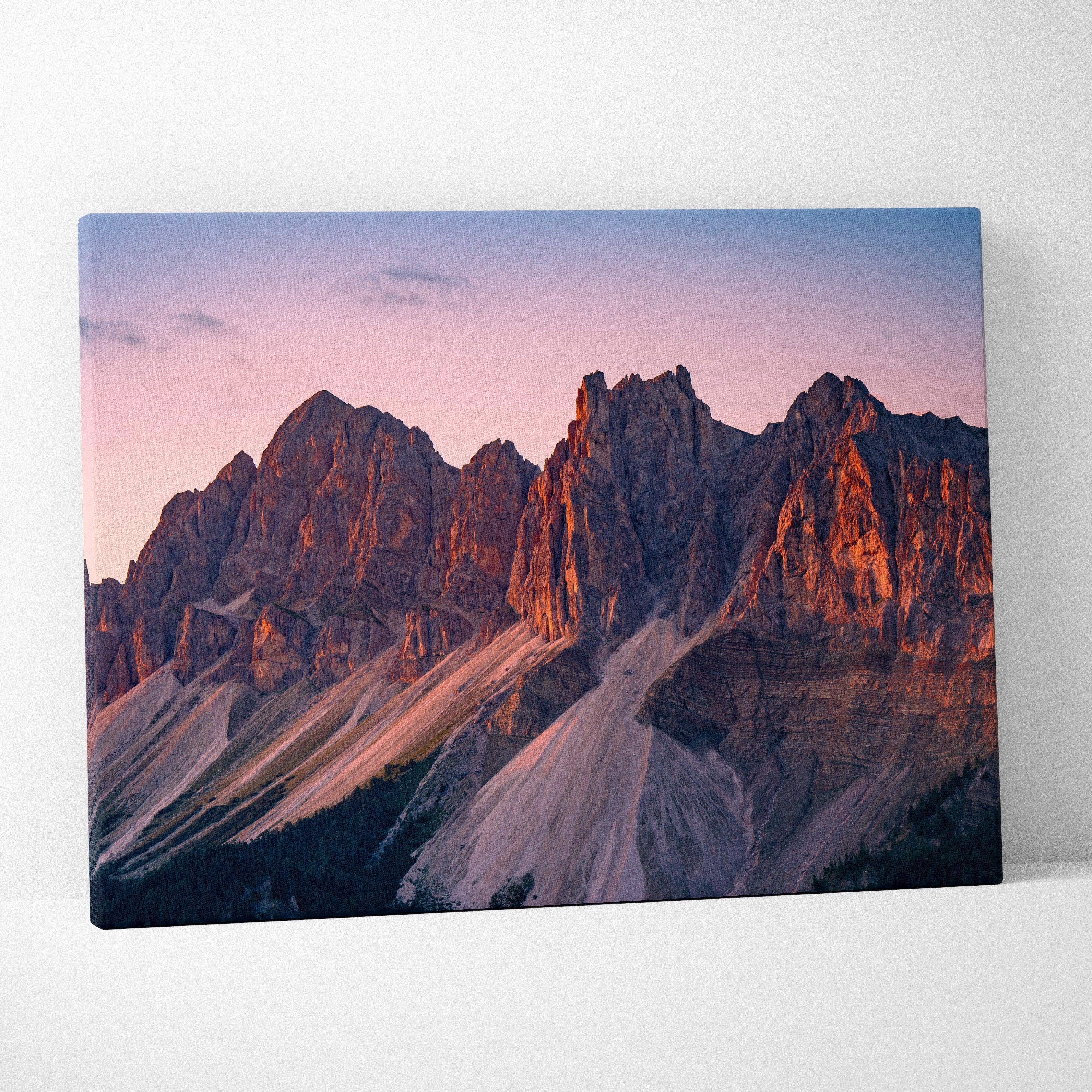 A rectangular canvas print of a mountain range at sunset in warm golden hour tones for living room decor