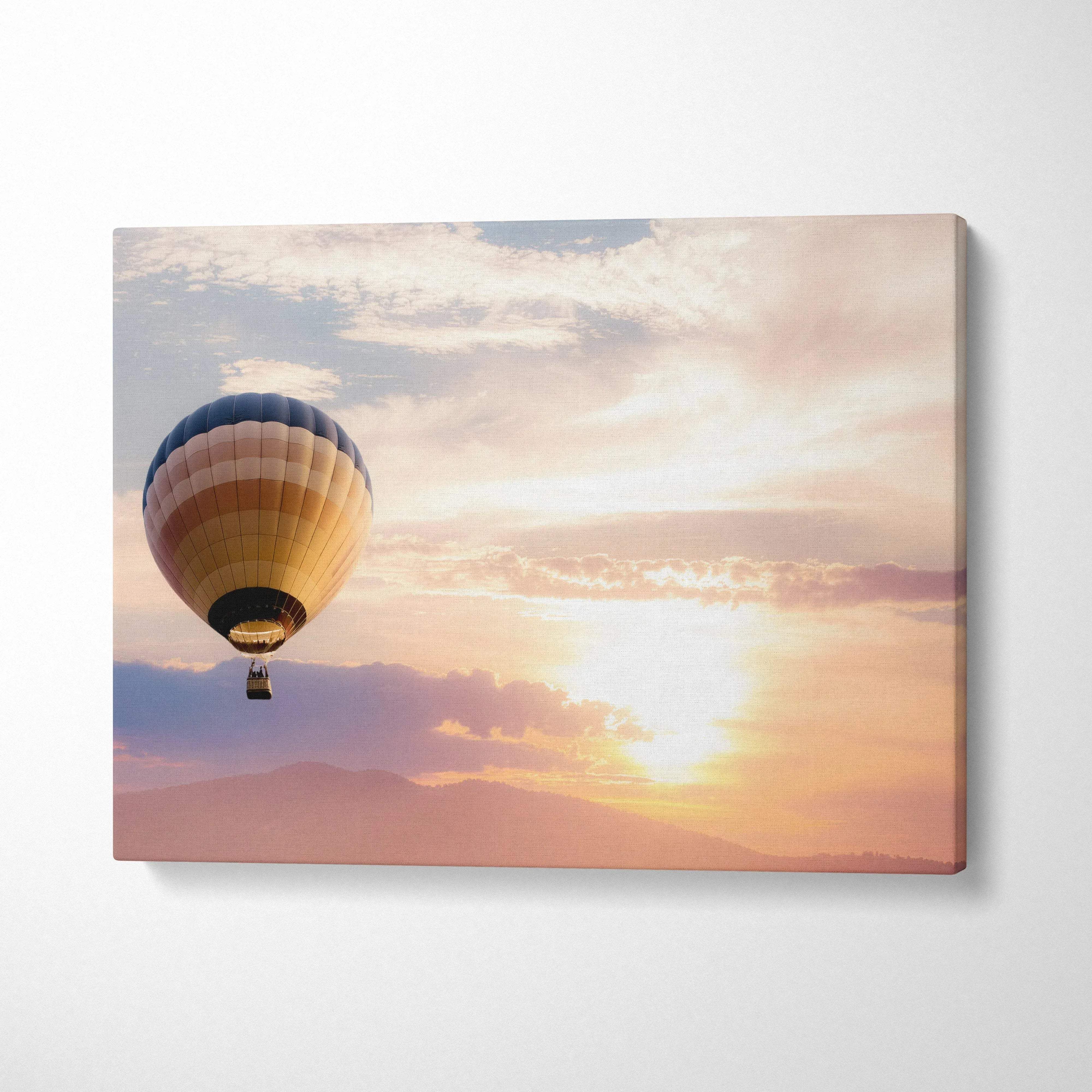Sunset landscape hot air balloon canvas wall art featuring a blue beige and gold striped balloon against a peach sky
