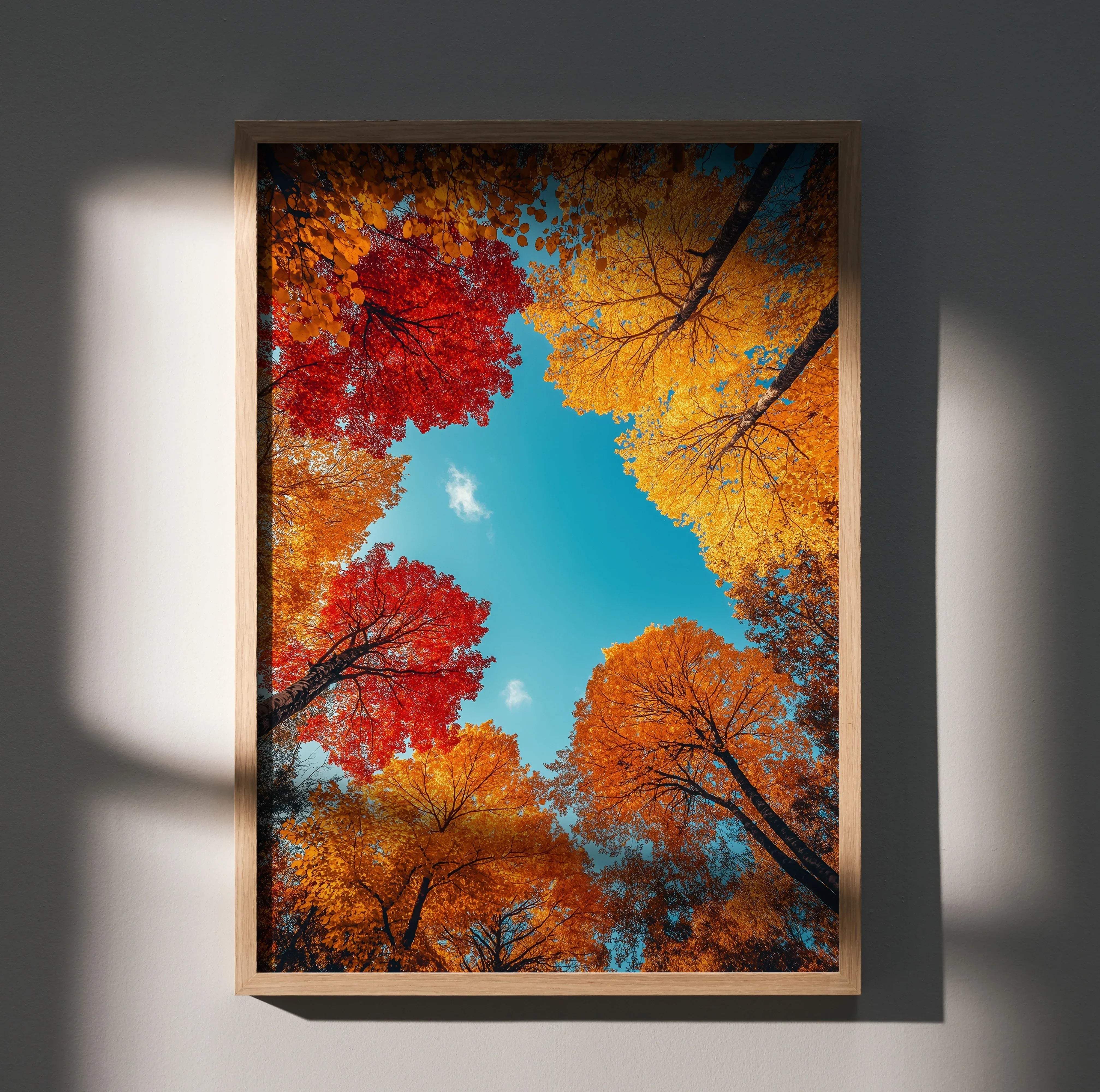 Framed vibrant autumn forest nature art print poster with red and golden leaves in a light wood frame against blue sky