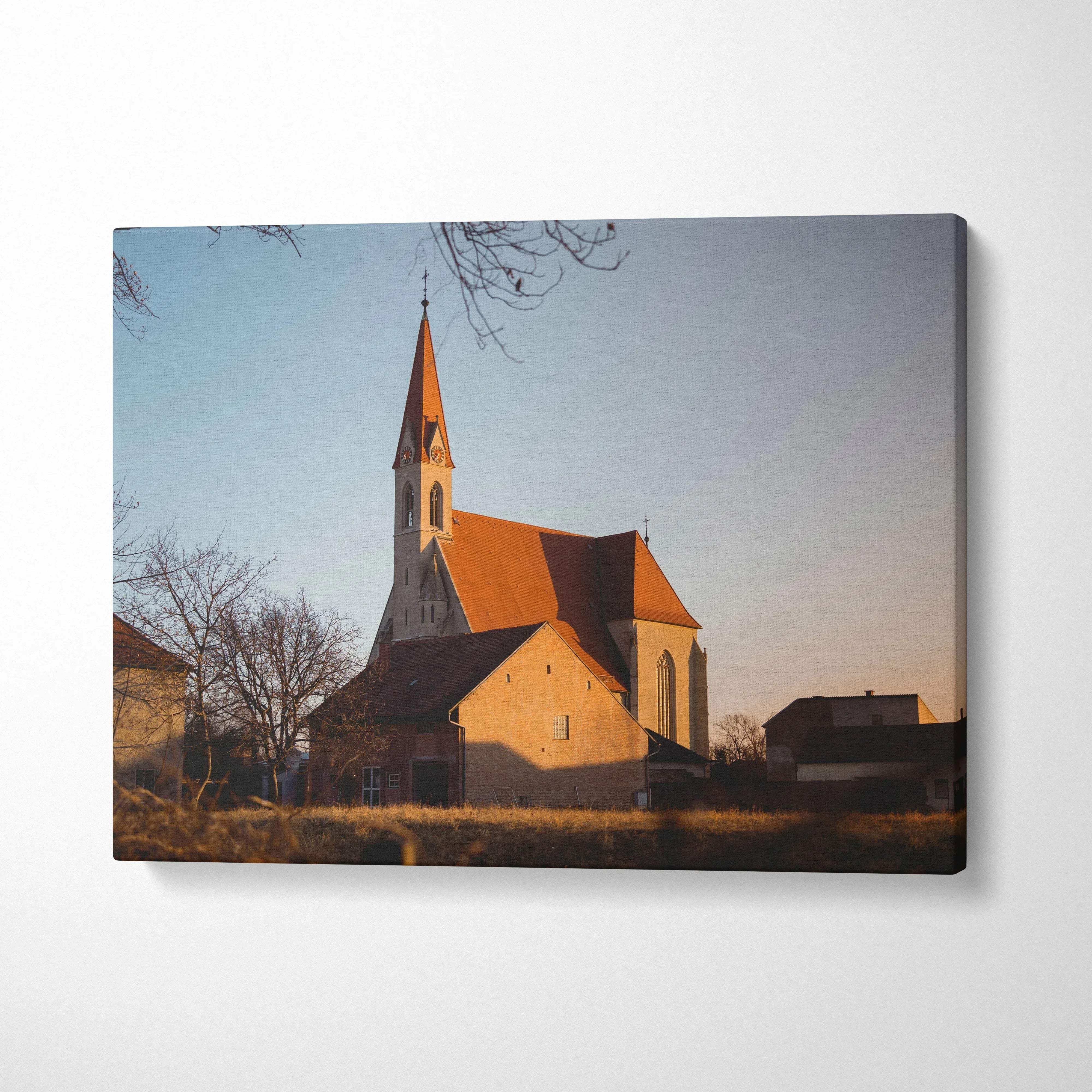 Canvas wall art featuring a warm sunset lit church with a tall steeple and surrounding buildings.