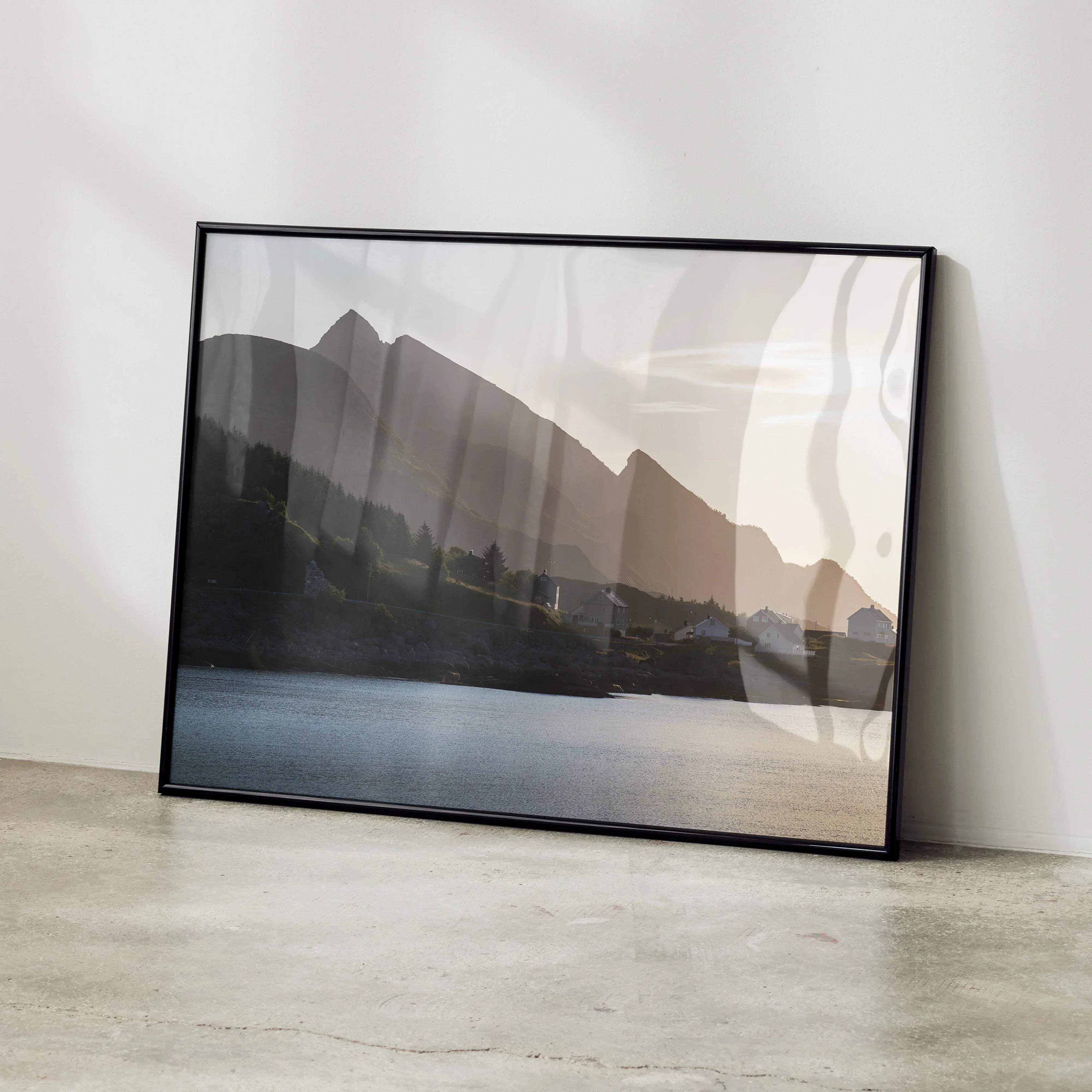 Black-framed landscape art print poster of serene mountain range reflected in calm water with soft sepia tones