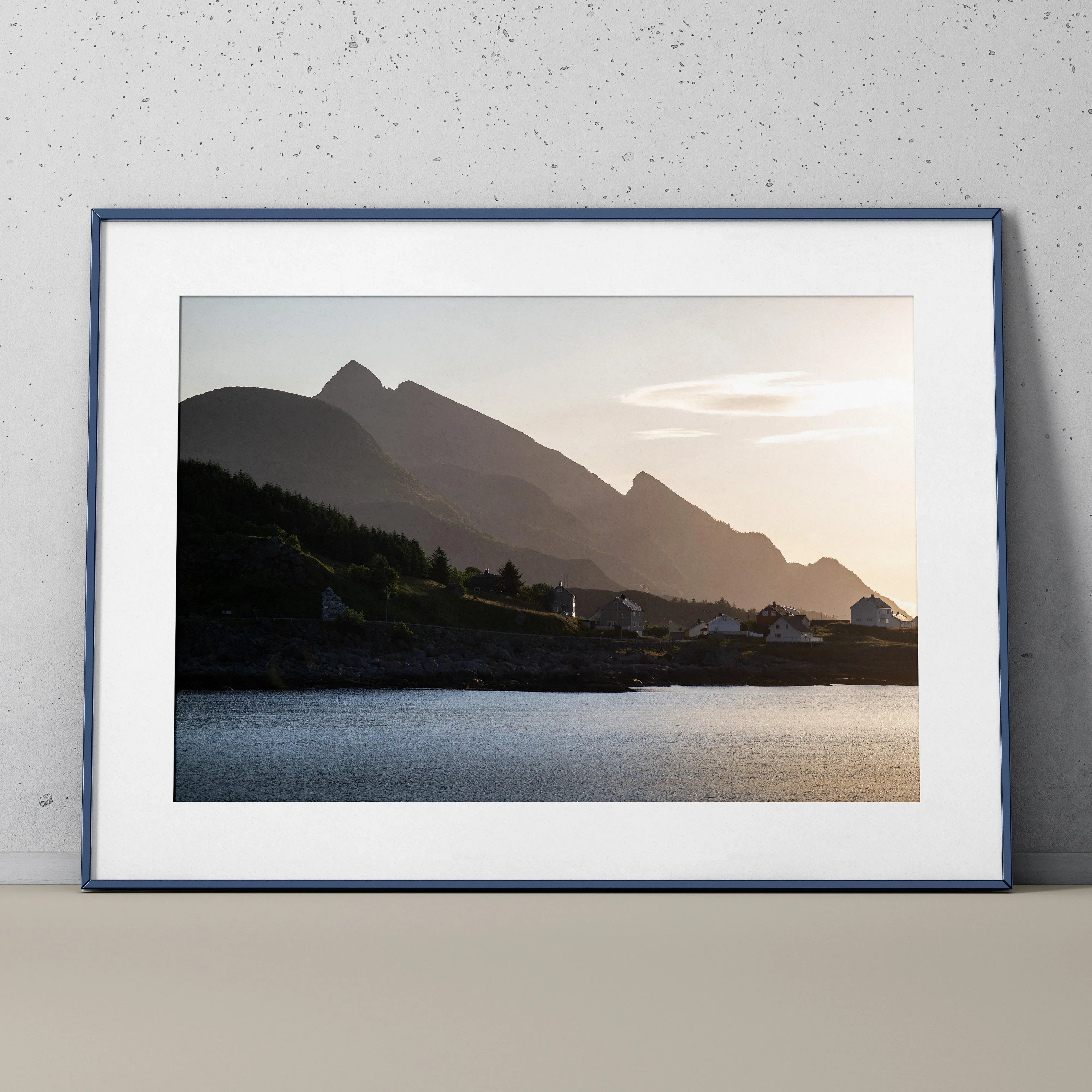 Framed wall art poster depicting mountains at sunset with calm water foreground and soft sky colors.
