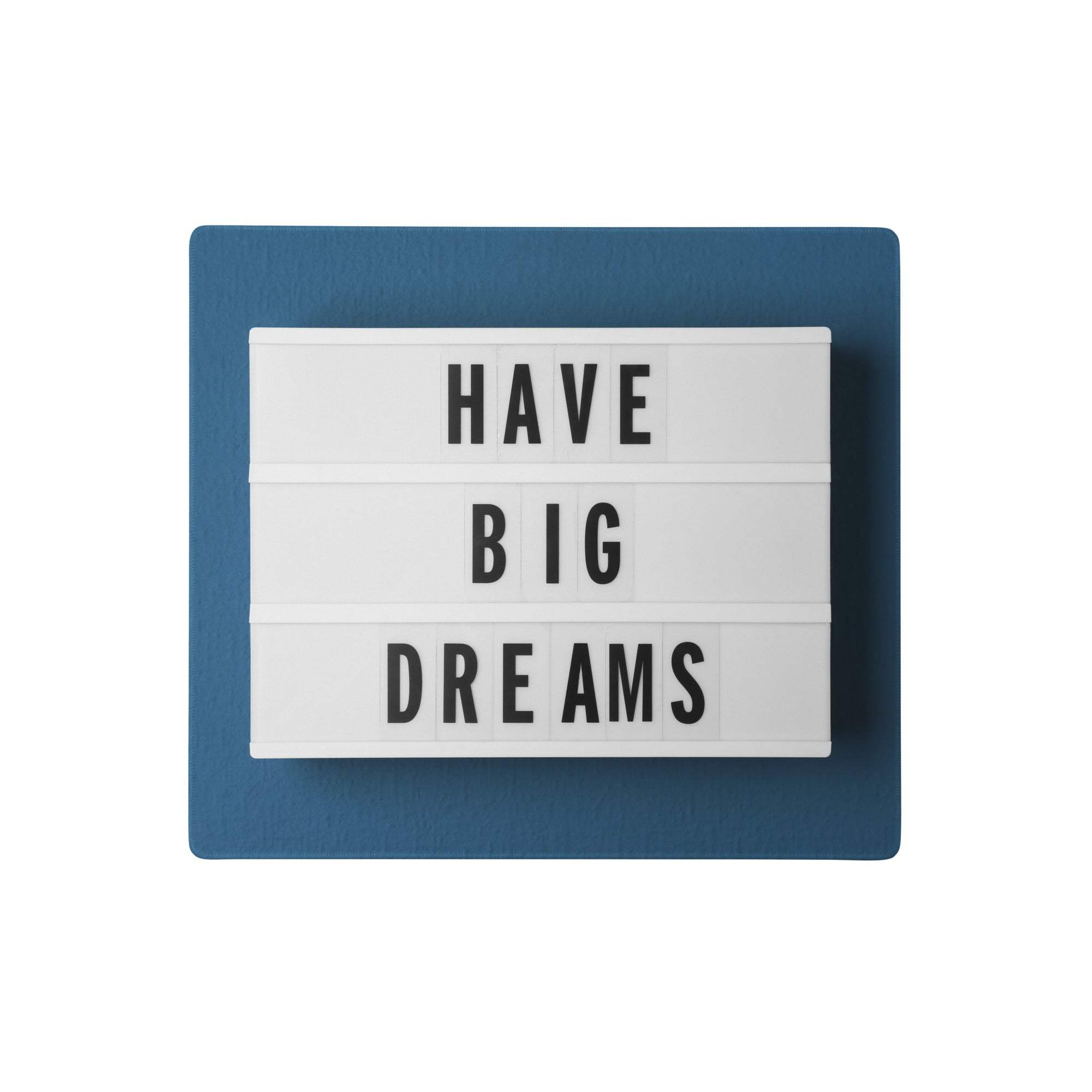Blue-framed lightbox with black typography displaying have big dreams as part of a motivational desk setup