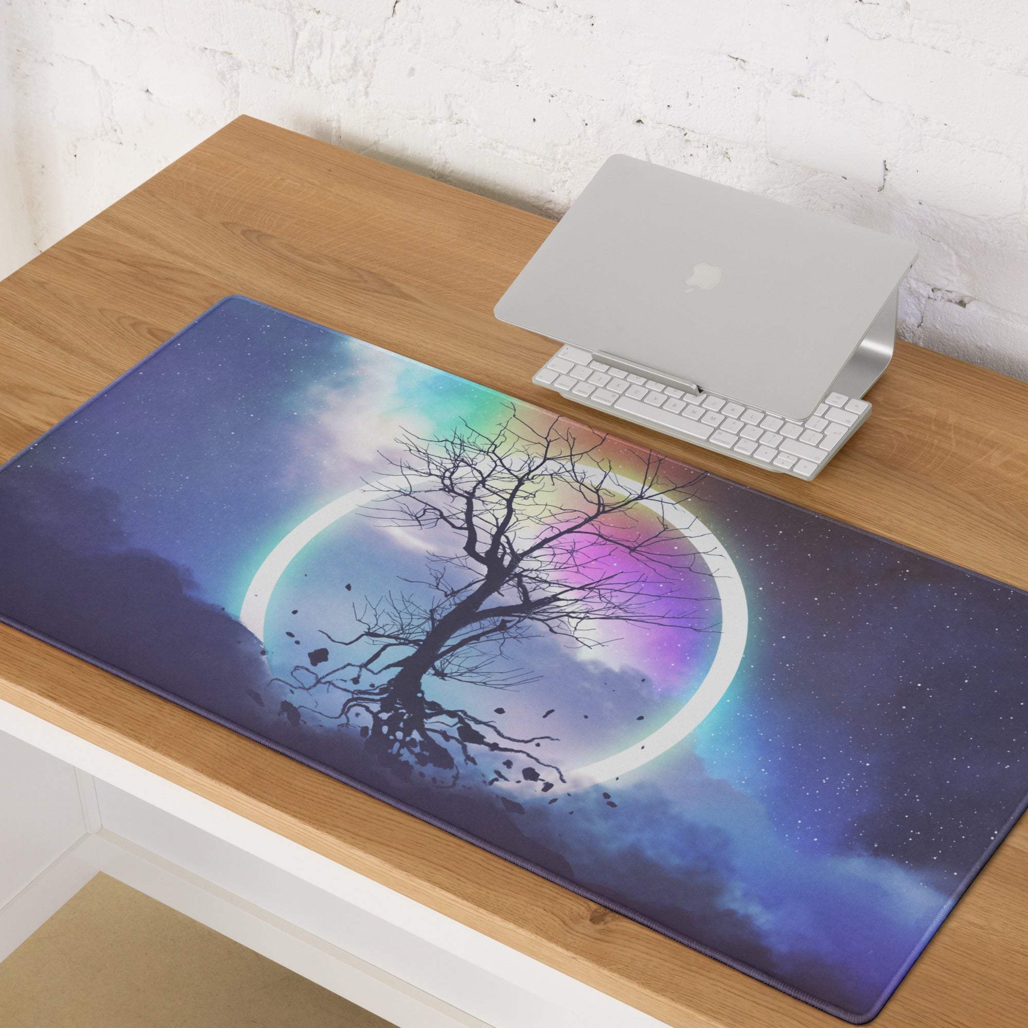 A rectangular soft textured mousepad with a bare tree silhouette against a vibrant rainbow night sky cosmic design