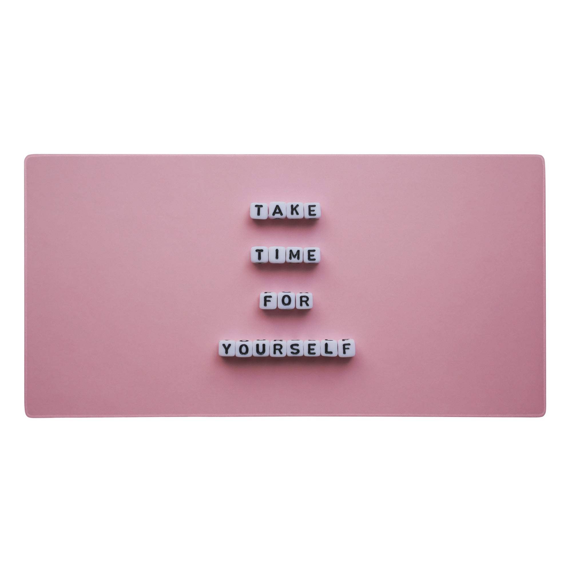 Pink rectangular magnetic board with white letter tiles displaying take time for yourself in a pastel pink desk mat setup