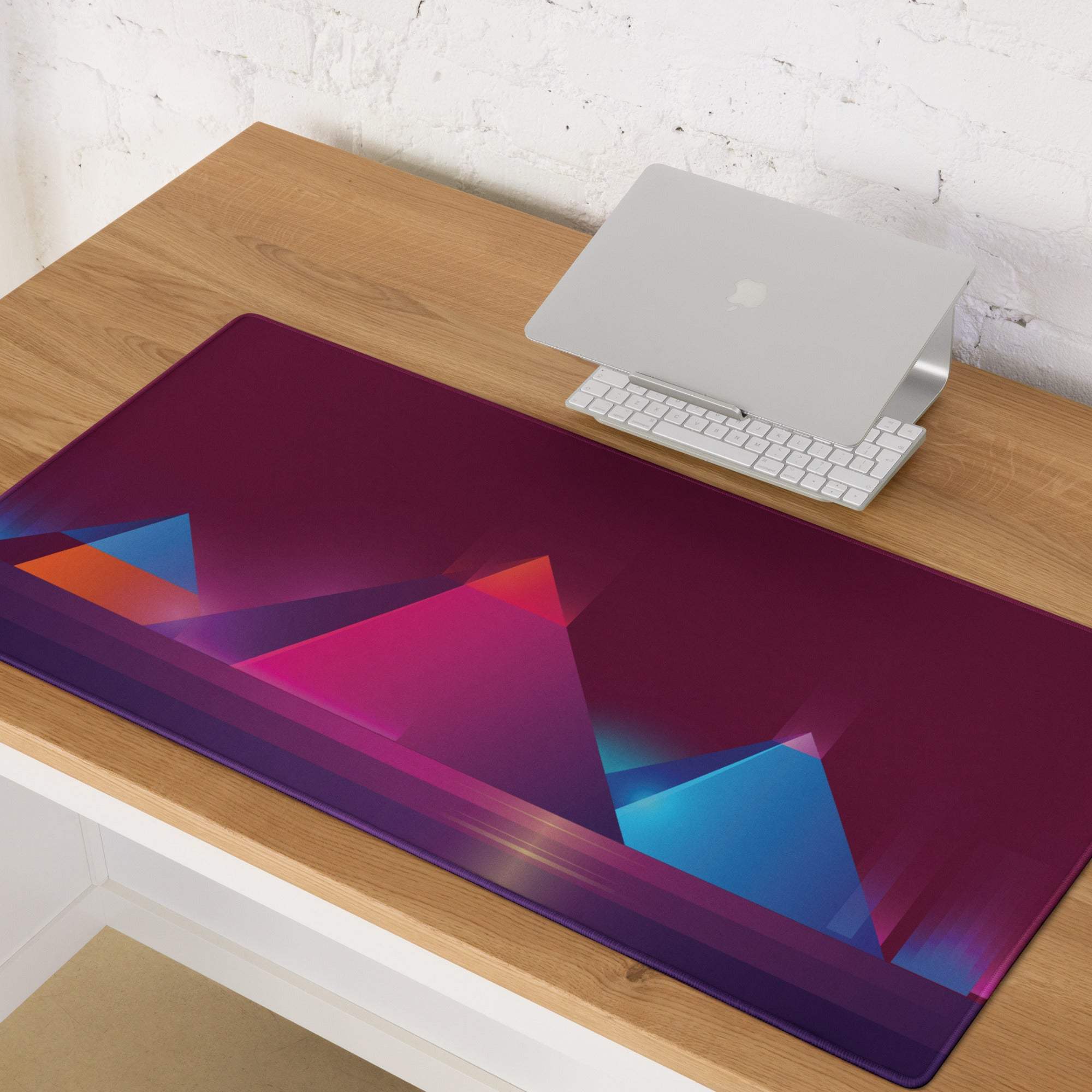 A rectangular glossy gaming mouse pad with a vibrant purple pink blue orange geometric mountain design