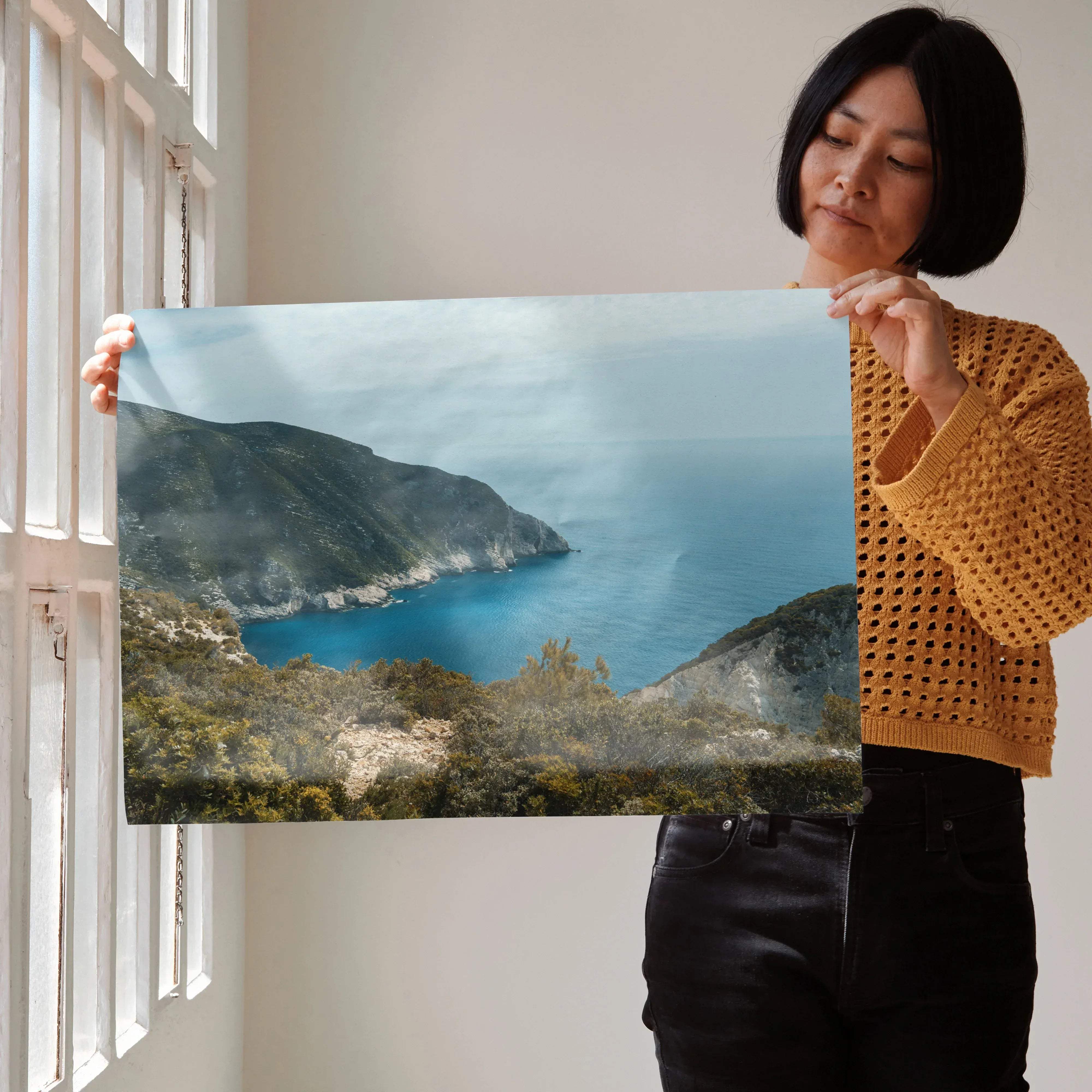 A rectangular framed wall art poster featuring a serene coastal landscape with deep blue waters and lush green cliffs